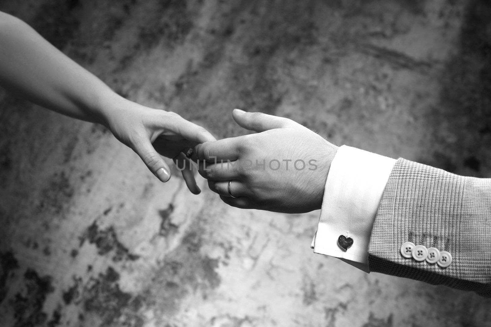 Female hands in man's hands on old wall background