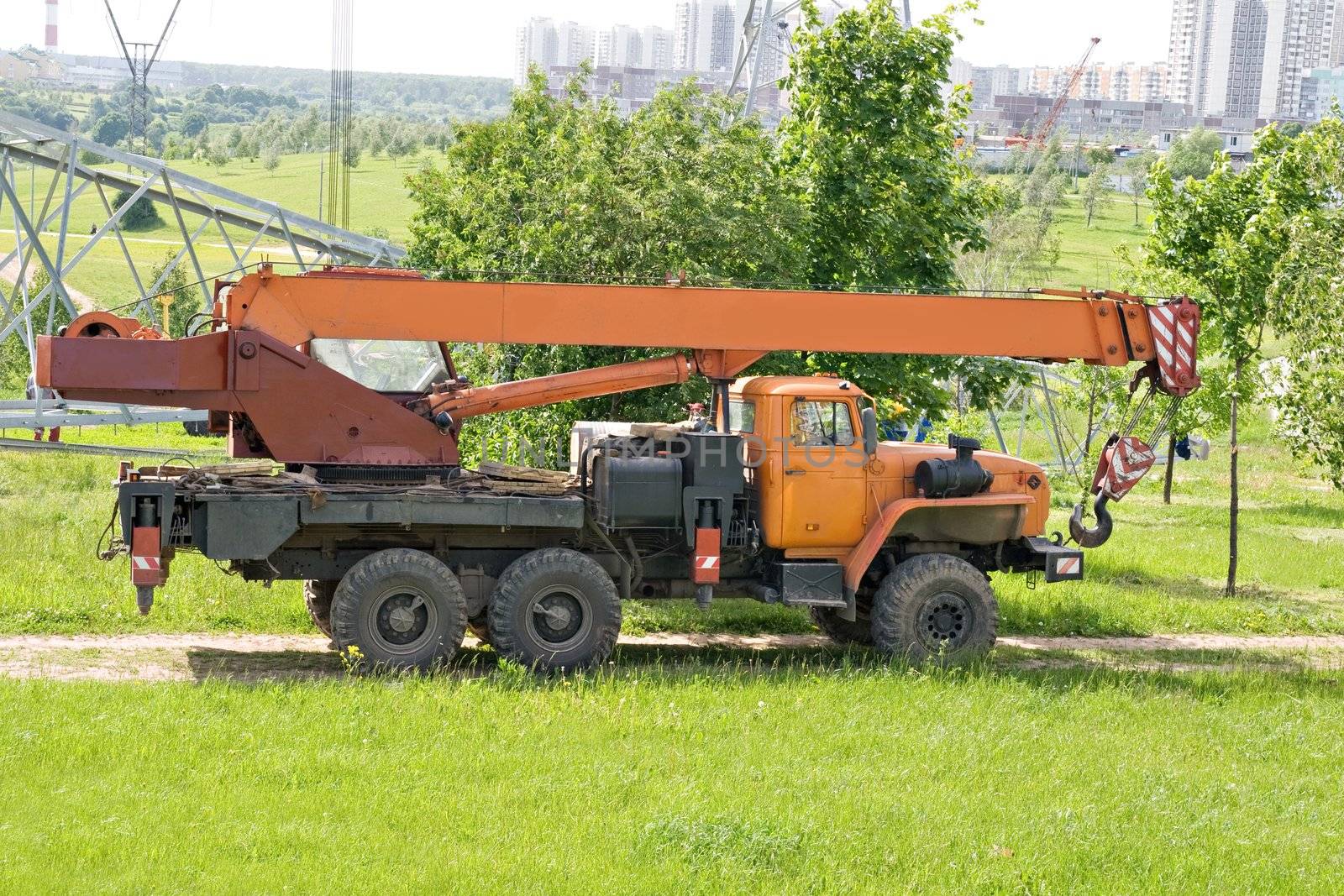 An orange crane truck standing in a city park