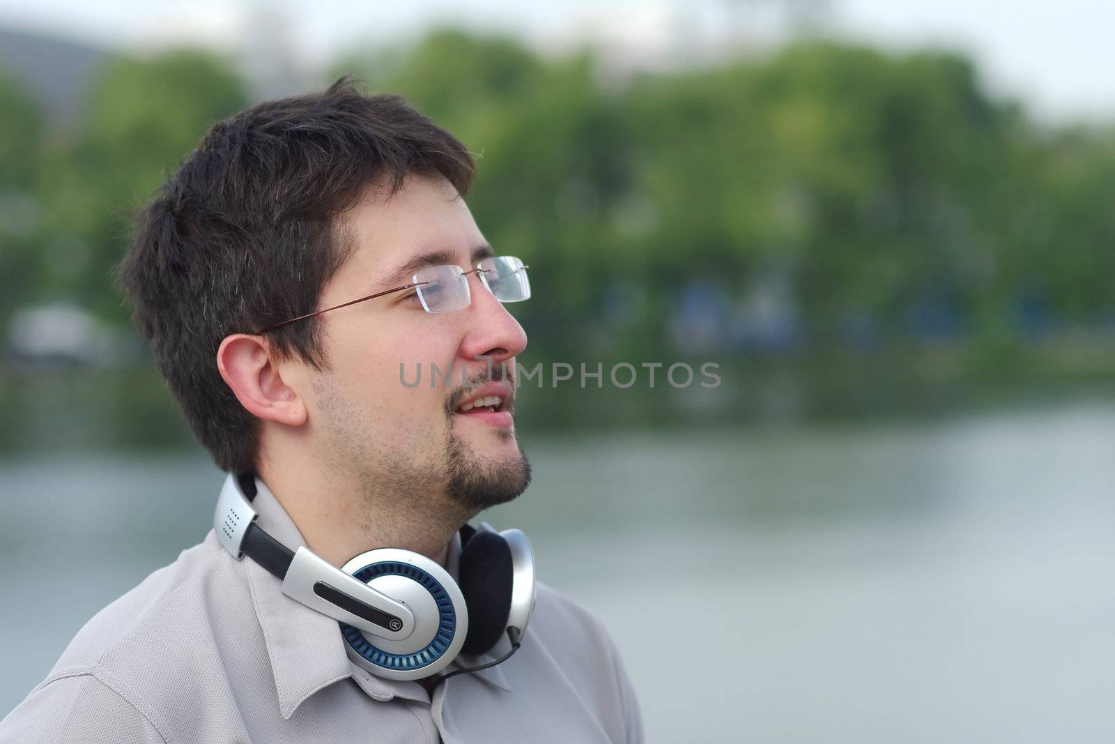 Young smiling man with headphones on city view background looking at something
