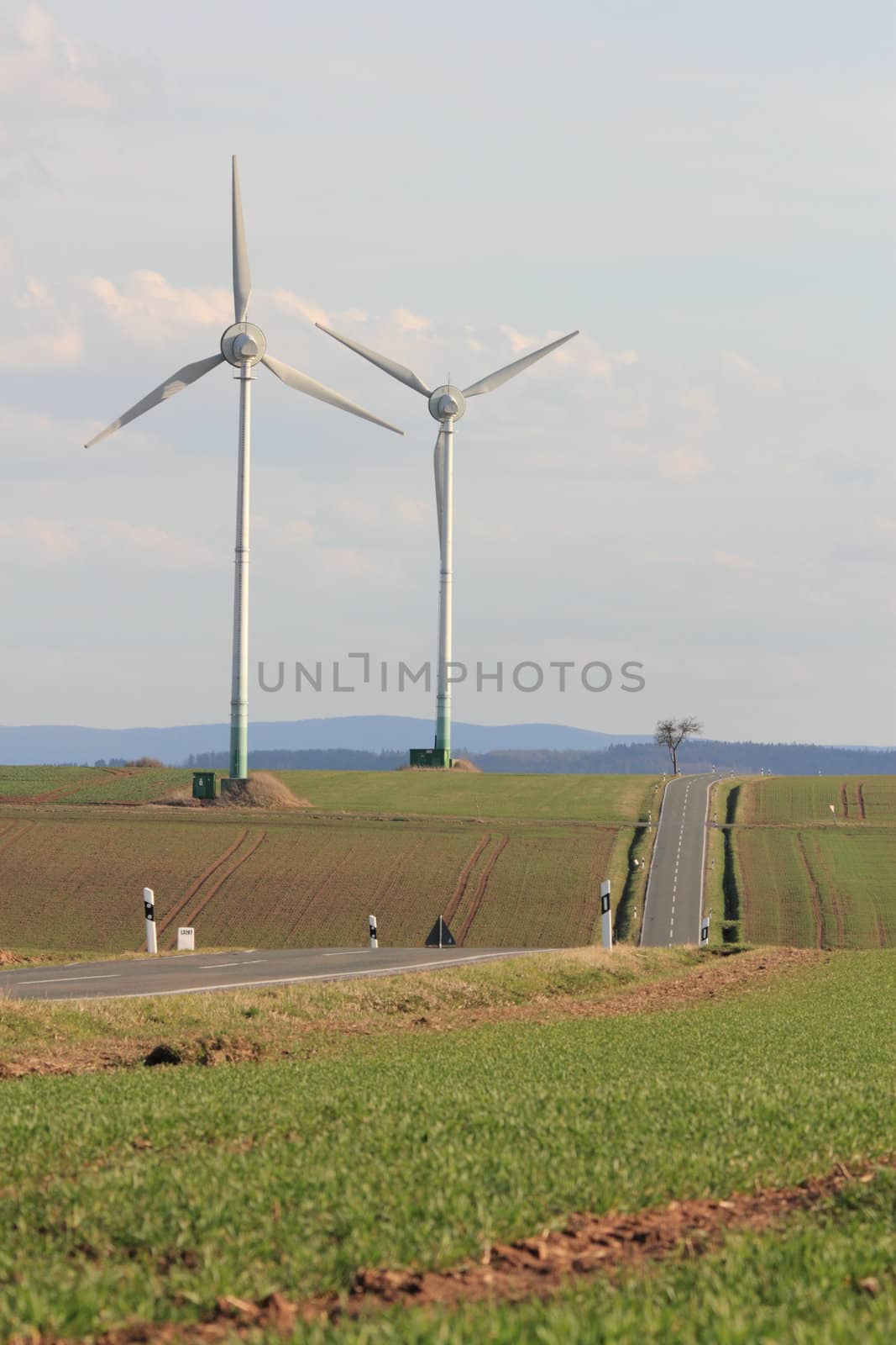 two wind turbines near a road in rural german landscape