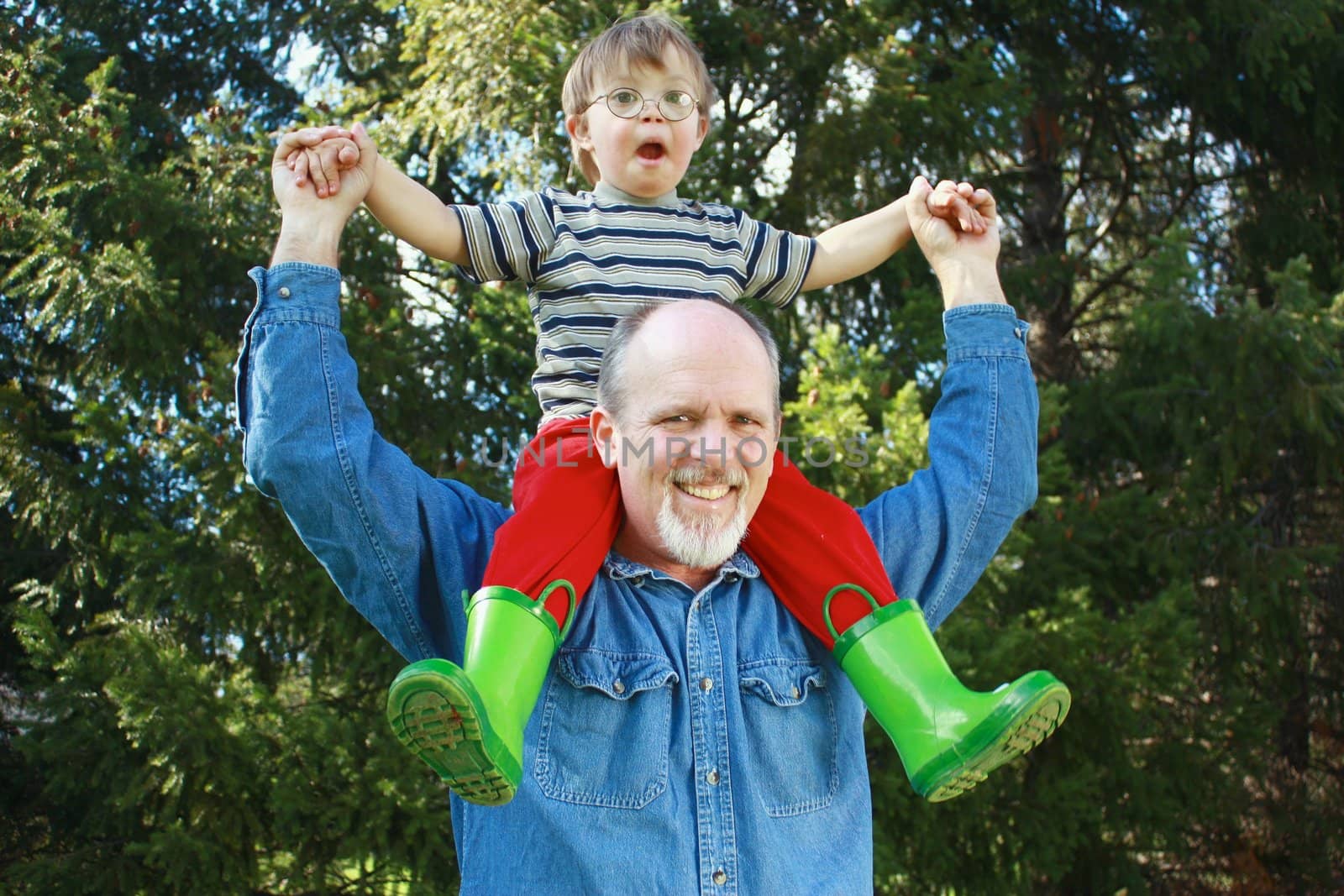 Father with son on shoulders and trees in background