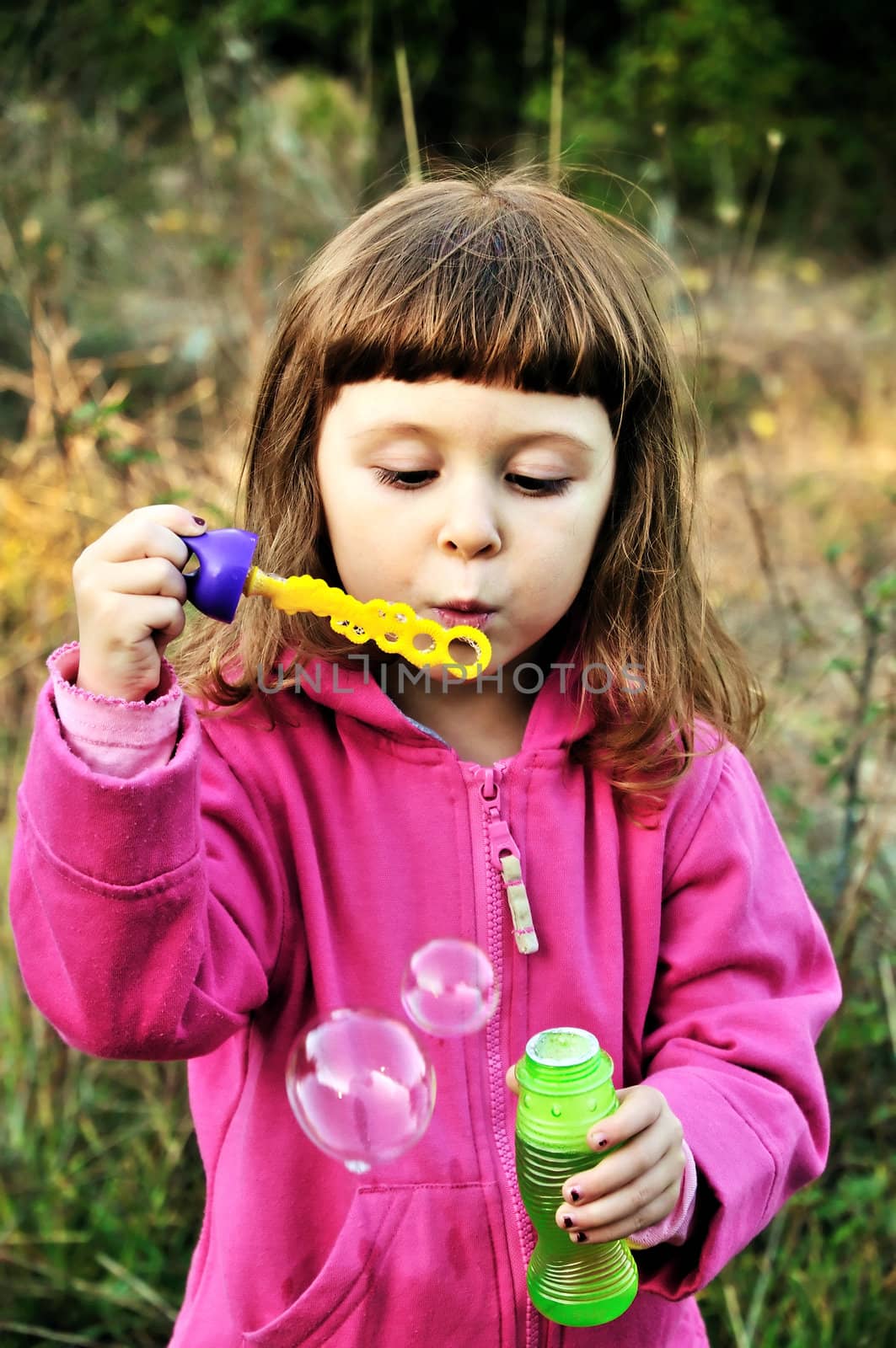 little girl blowing soap bubbles in autumn forest
