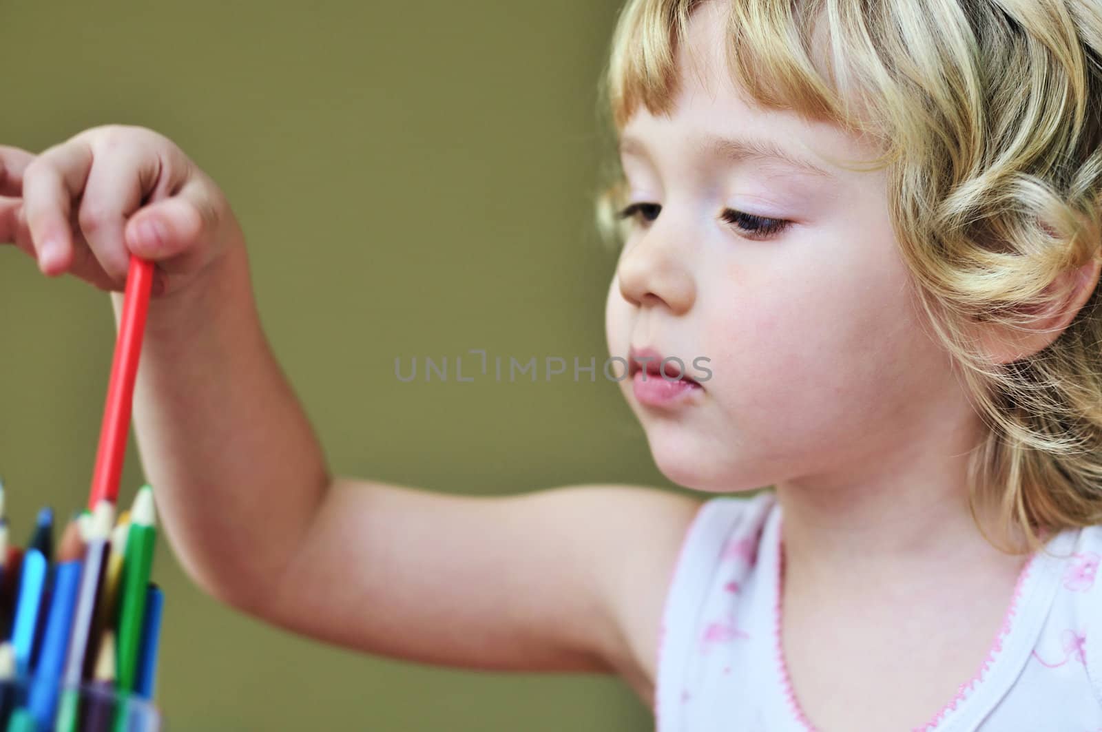 little lovely curly girl with pencils in soft focus