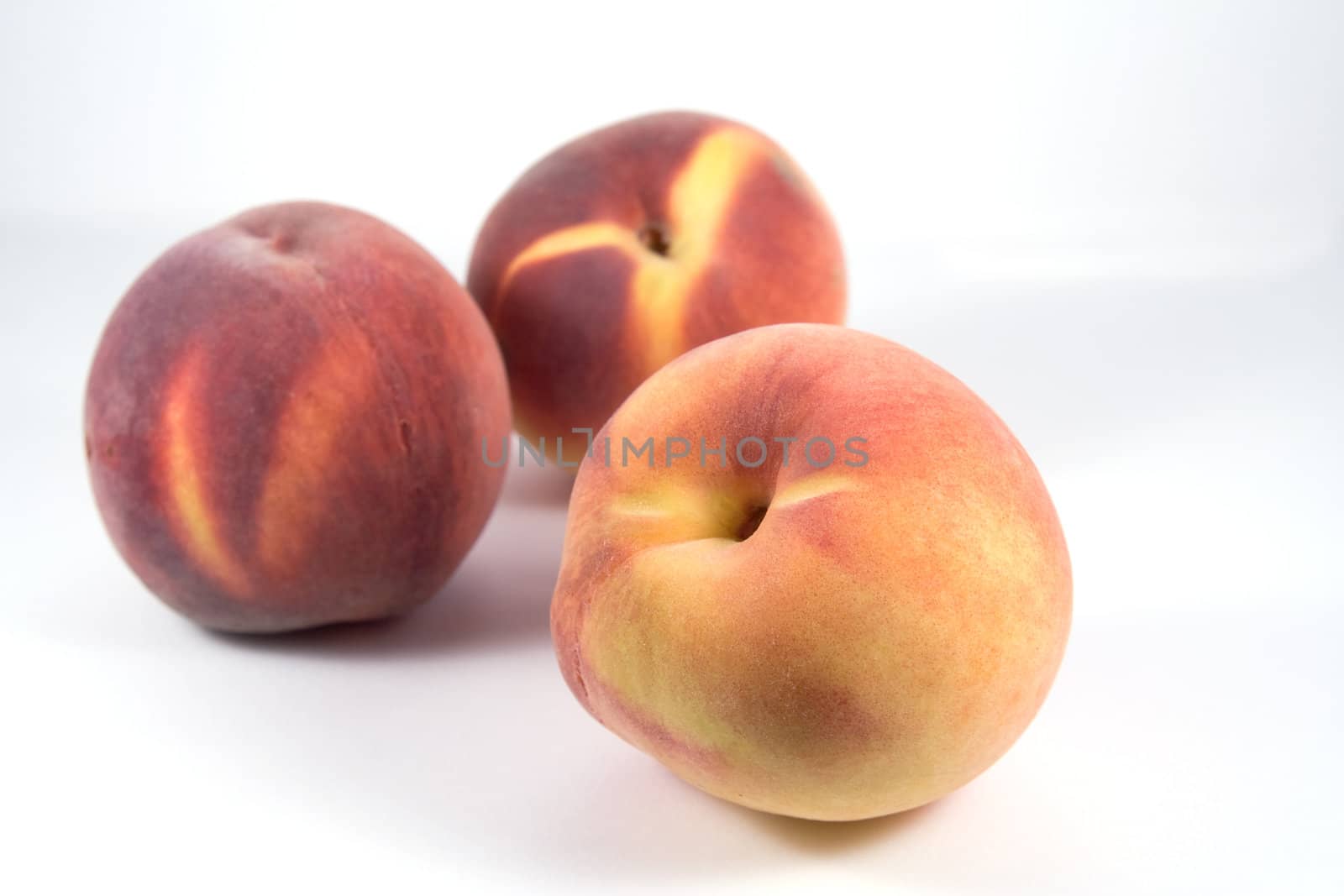 Three ripe peaches on white background. Focus on foreground one
