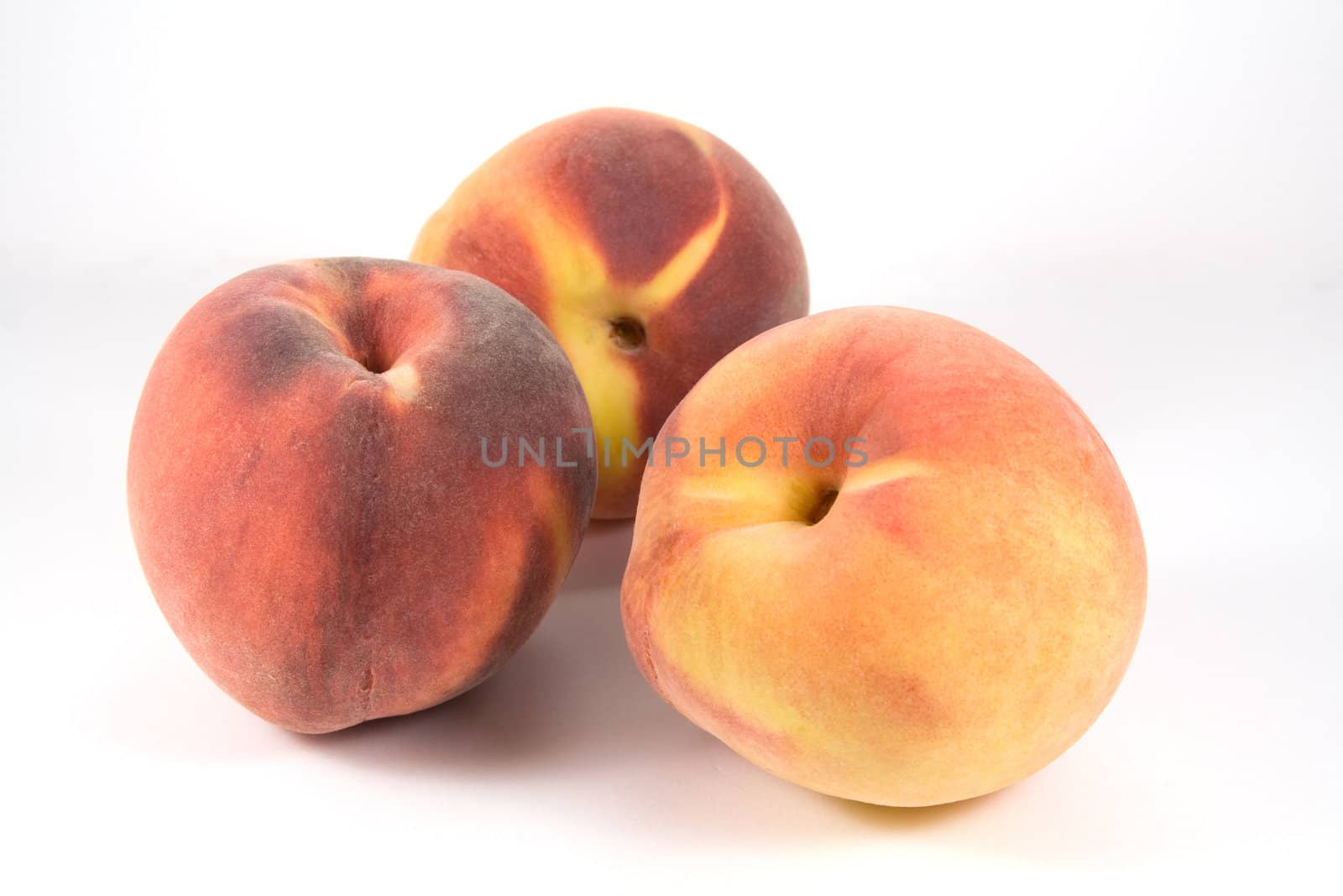 Three ripe peaches on white background
