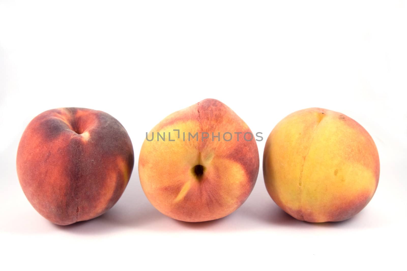Three ripe peaches abreast on white background