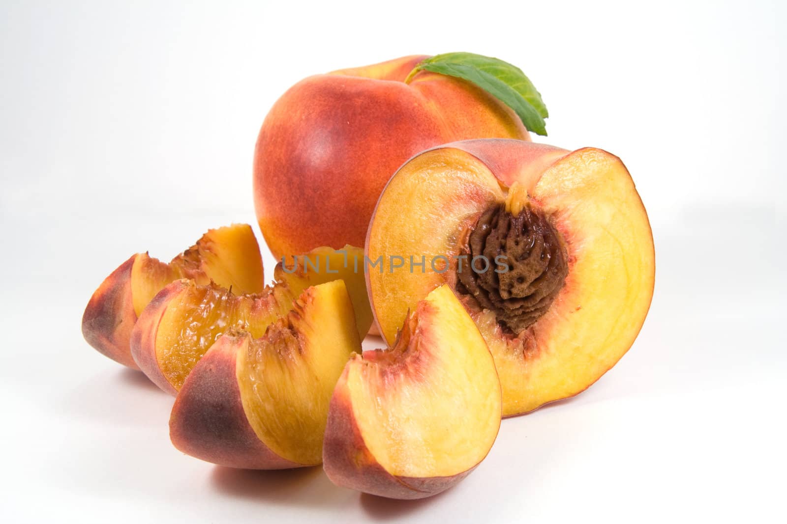Nectarine, half of peach with pit and pieces on white background