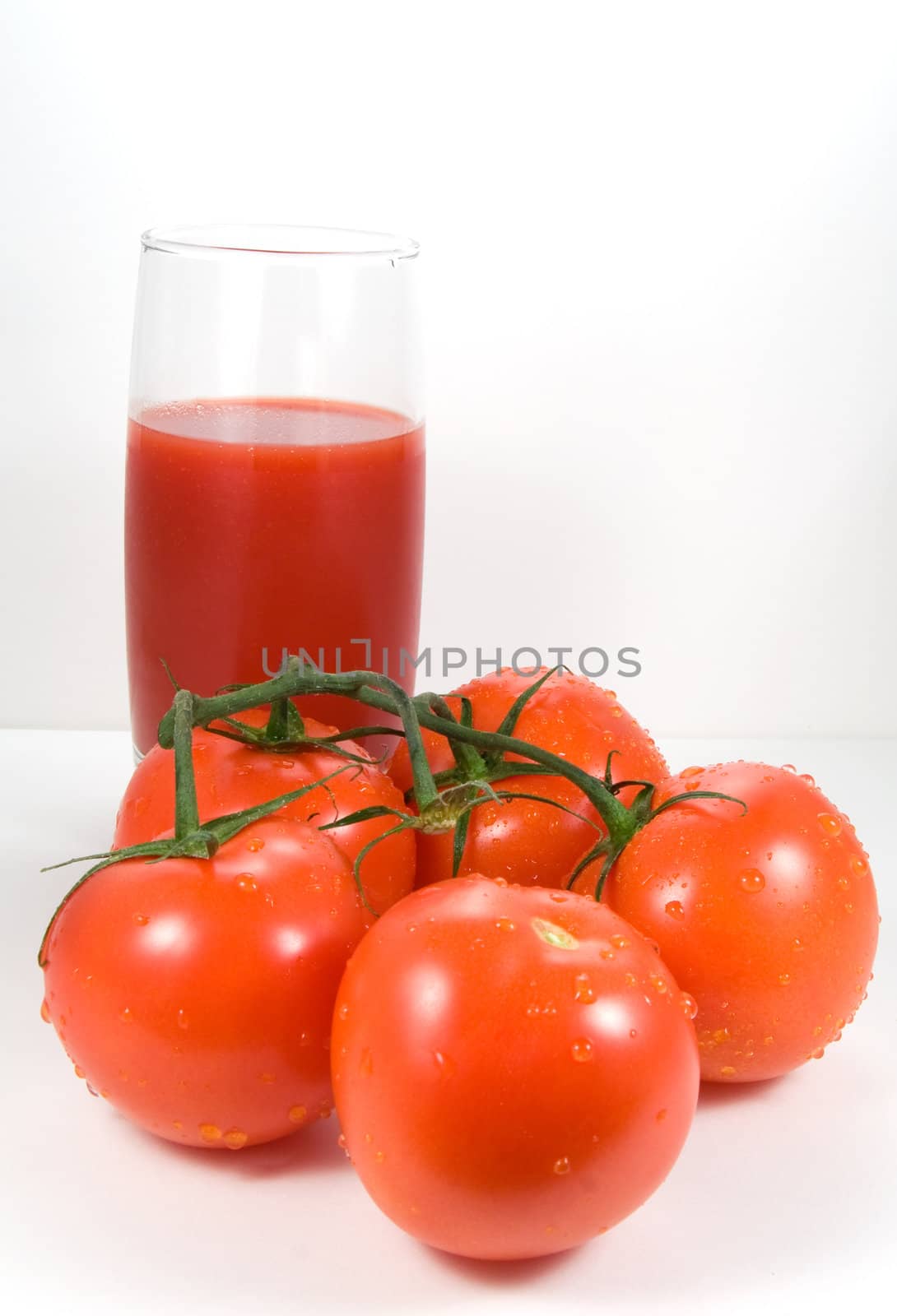 Tomatoes on the vine and glass of juice by serpl