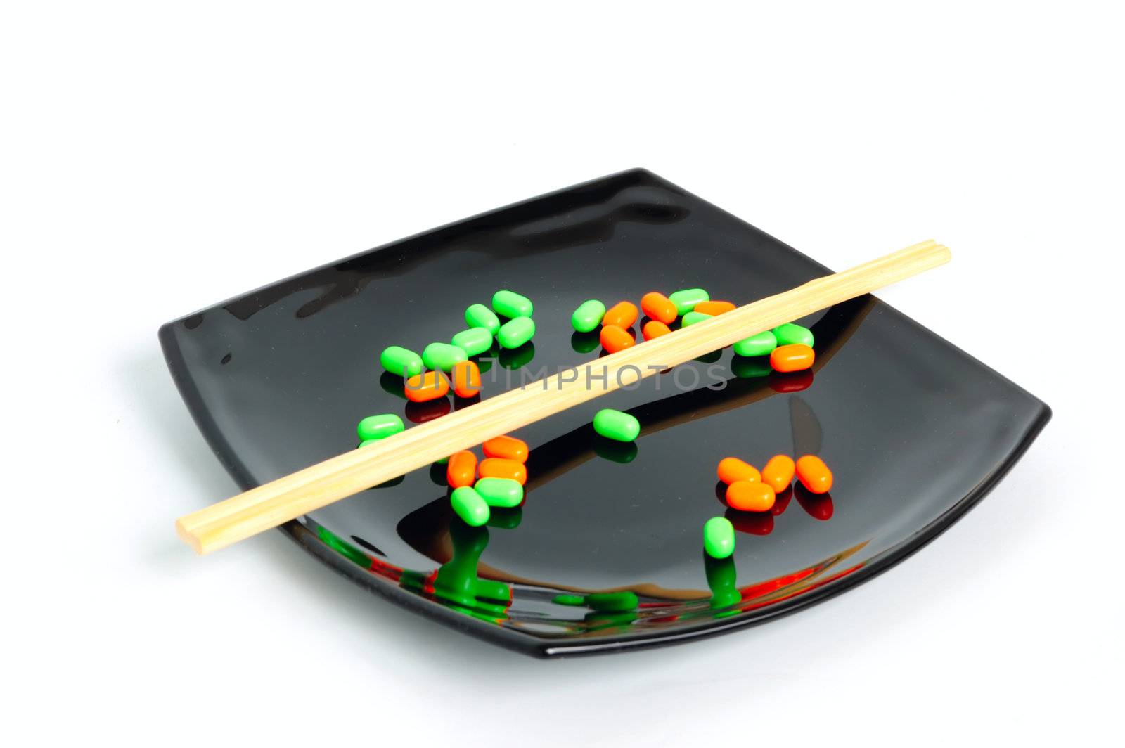 chemical diet - colored pills on black asian plate and chopsticks
