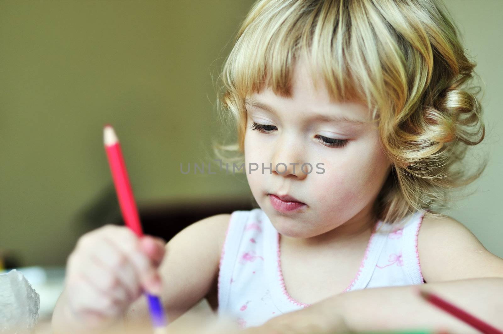serious little girl drawing in soft focus
