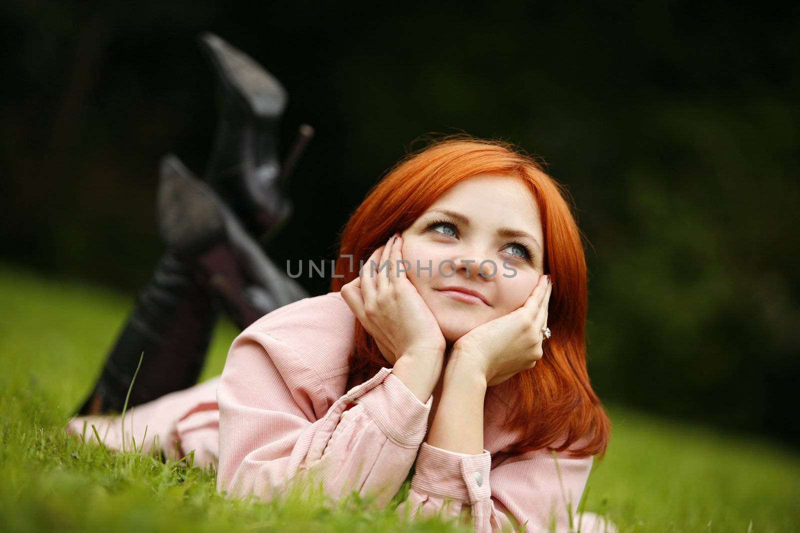 Portrait of the girl with red hair in a grass
