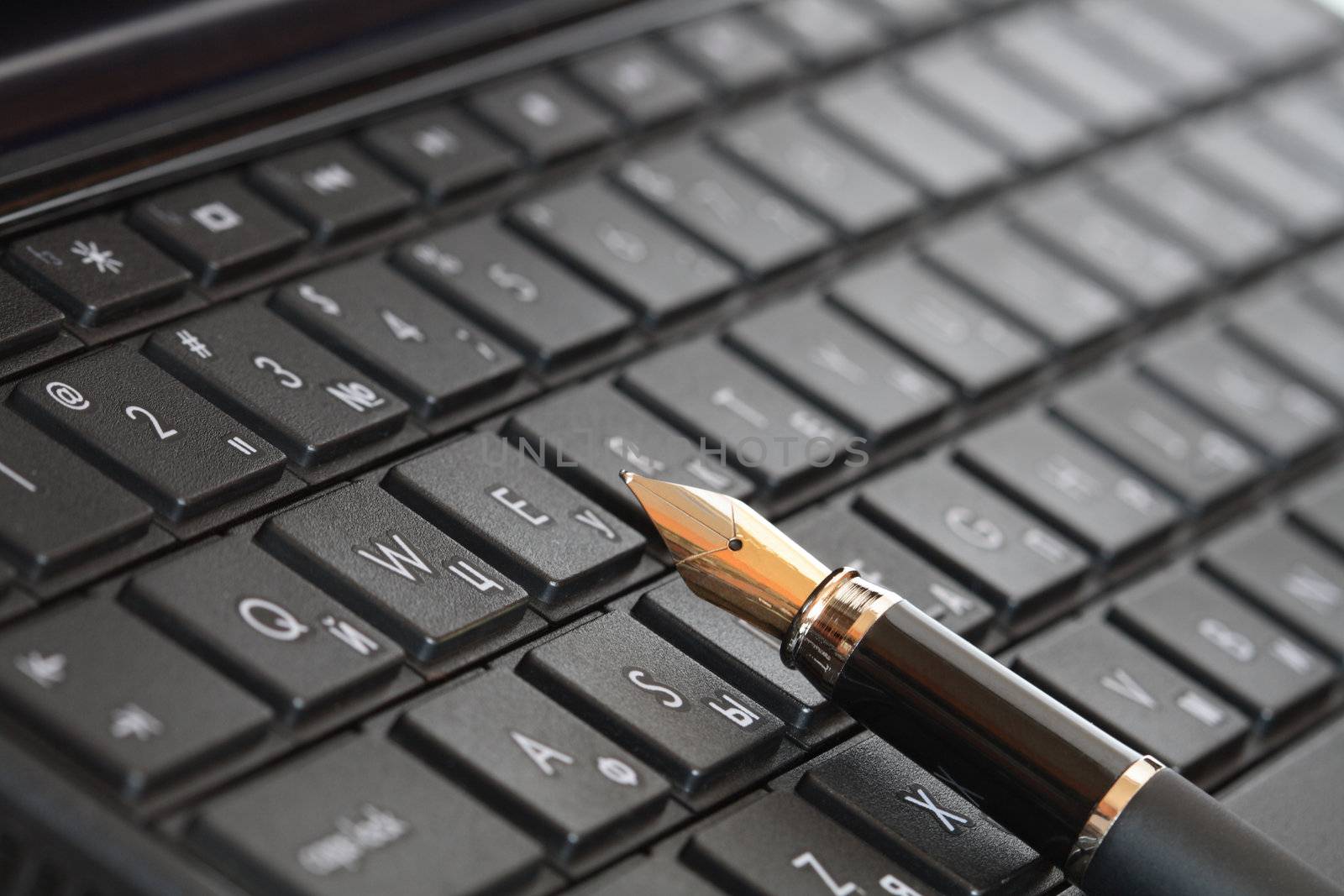 Closeup of fountain pen lying on black computer keyboard