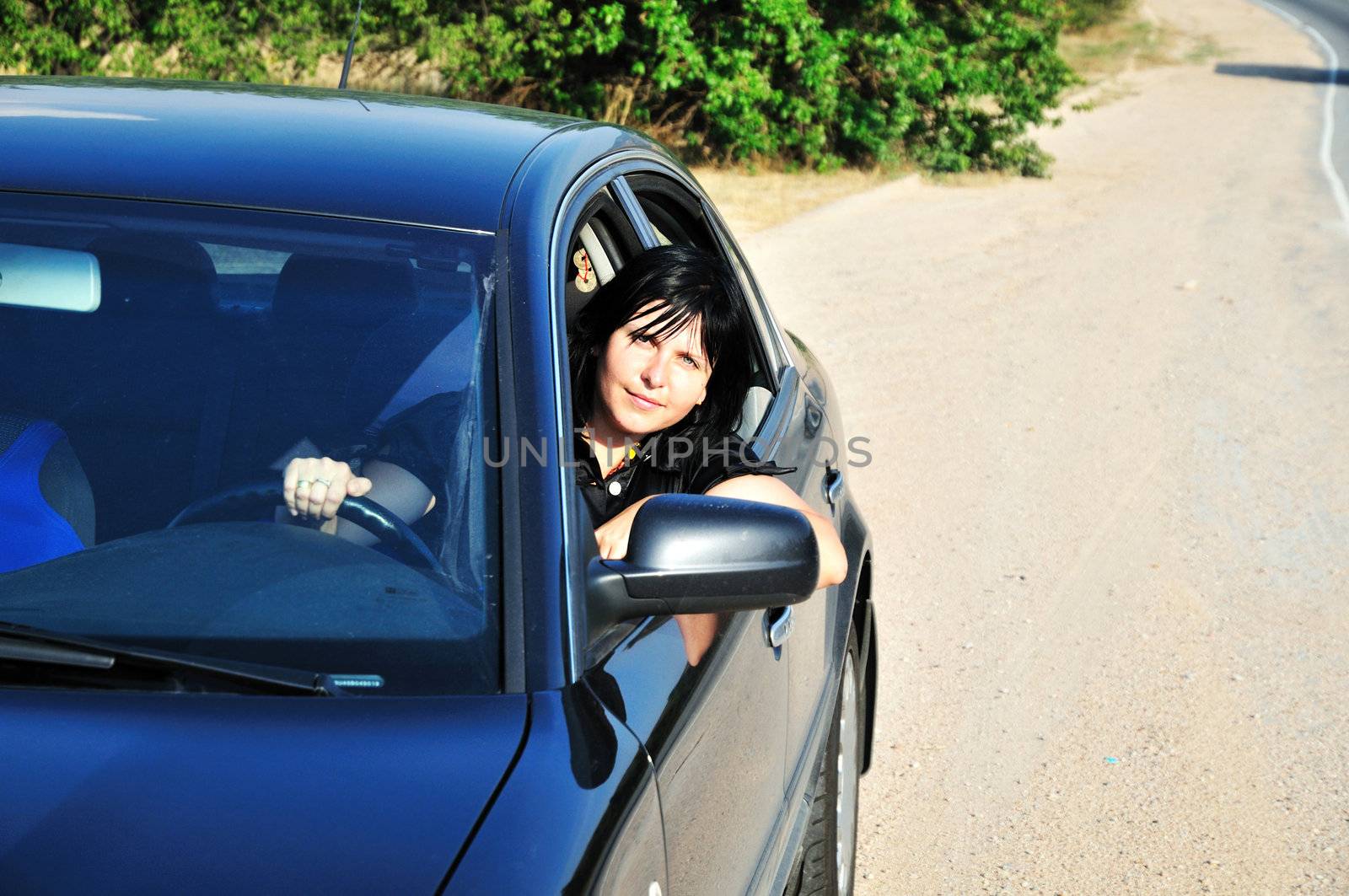 young brunette woman driving a blue car