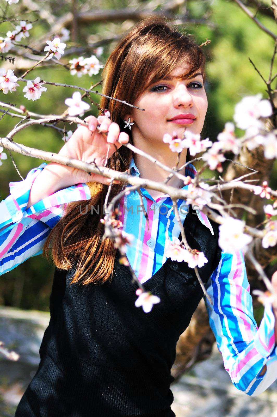 attractive young girl standing with first spring flowers of sakura