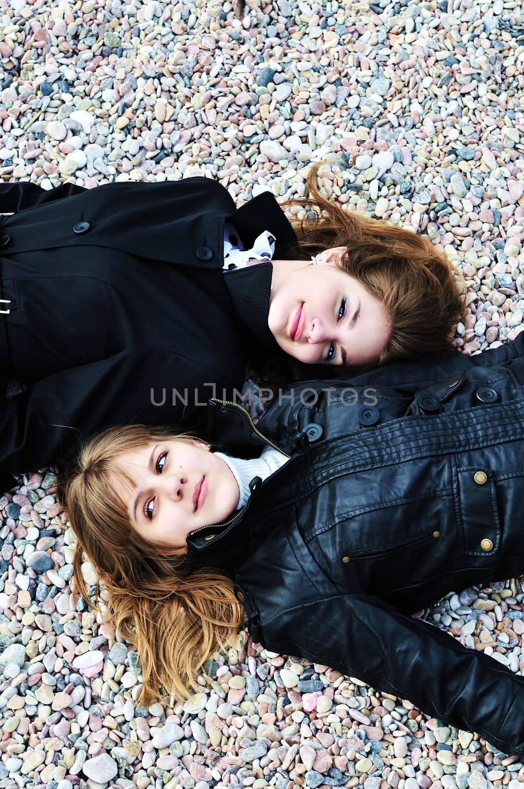 two teen girls laying on the pebble by Reana