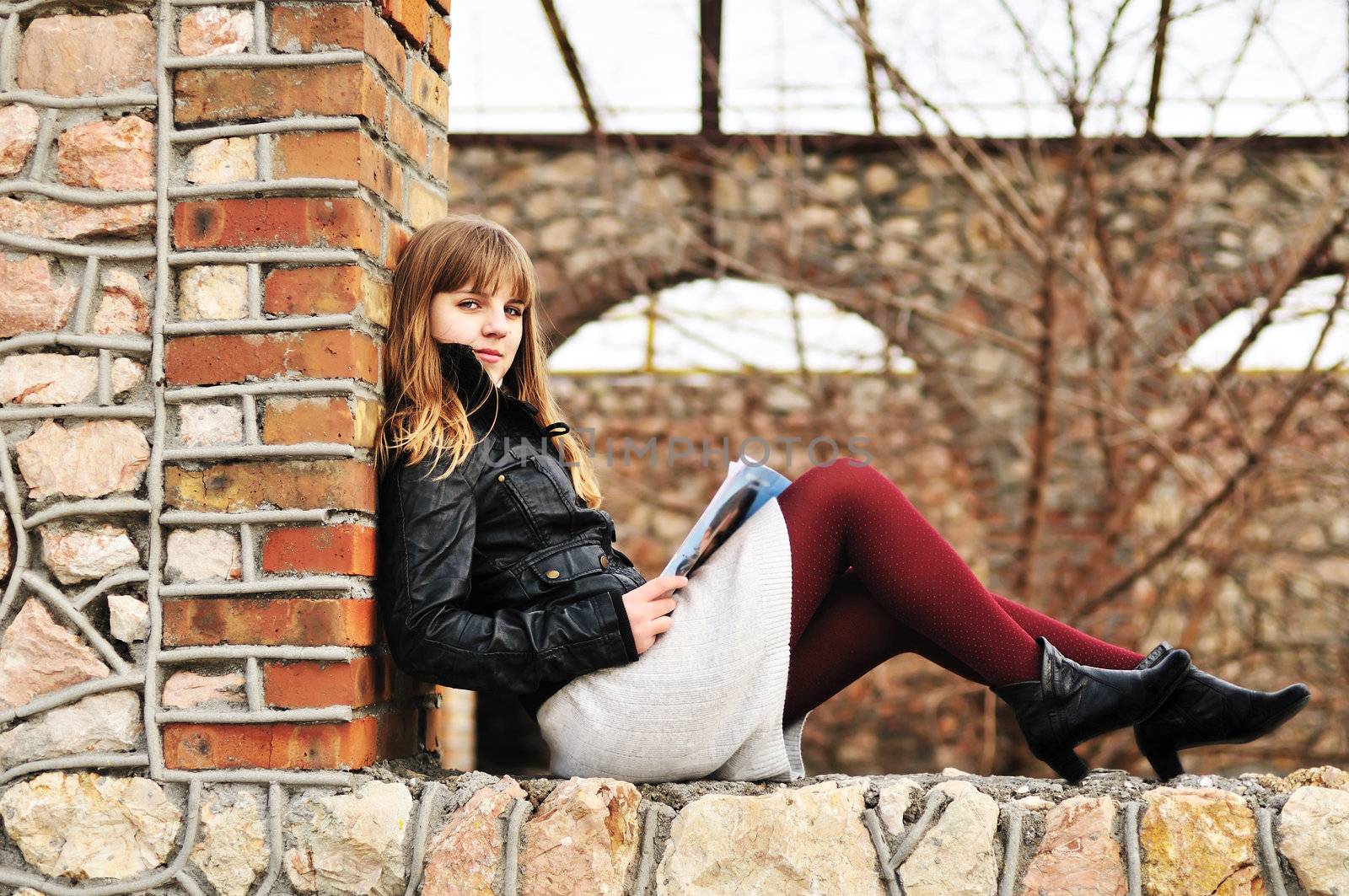 teen girl reading magazine outdoors on the window