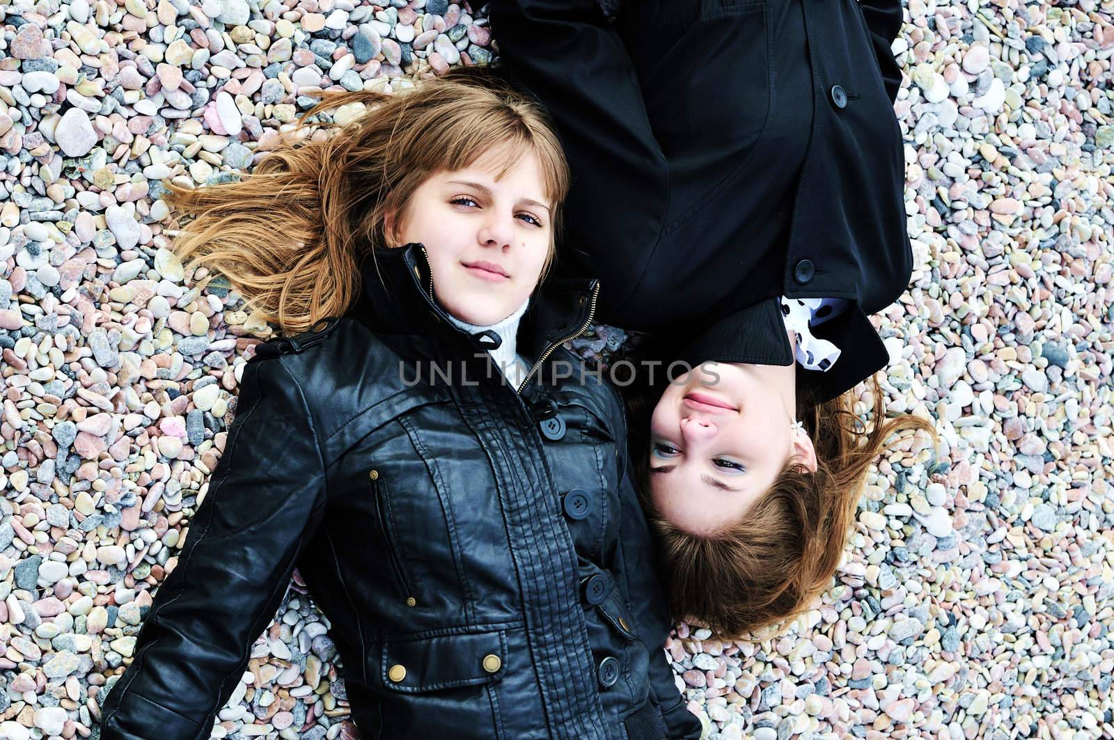 two lovely teen girls laying on the pebble in spring time

