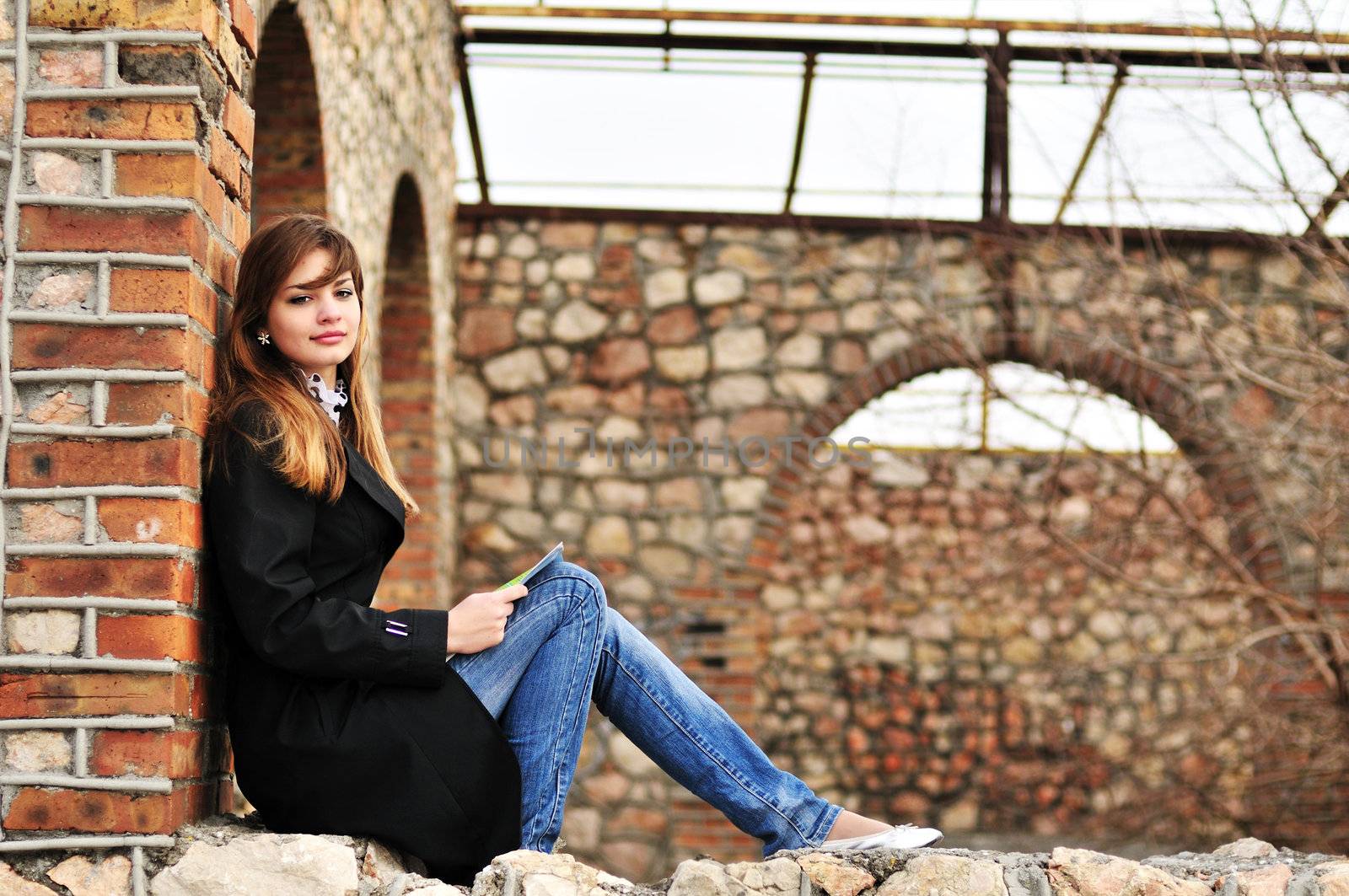 pretty teen girl reading  outdors on the brick window