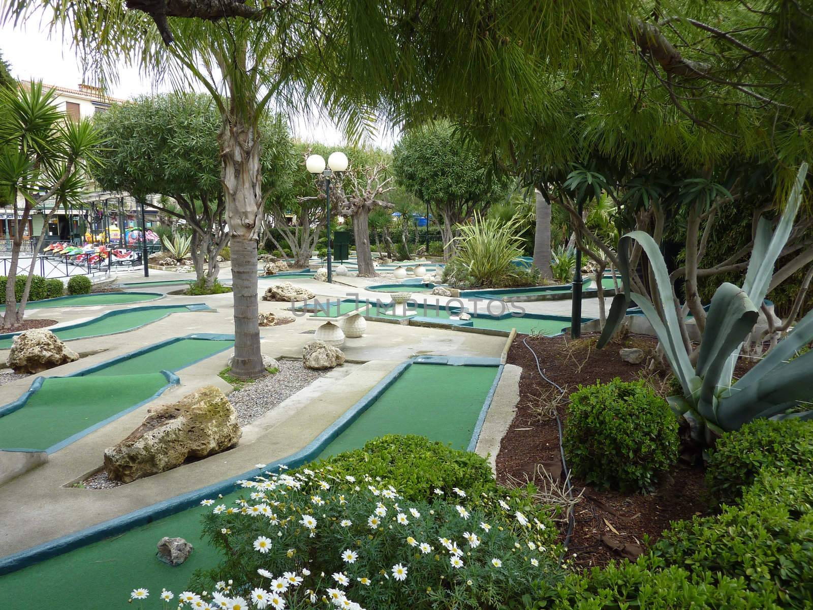 Green minigolf game among plants, trees and flowers