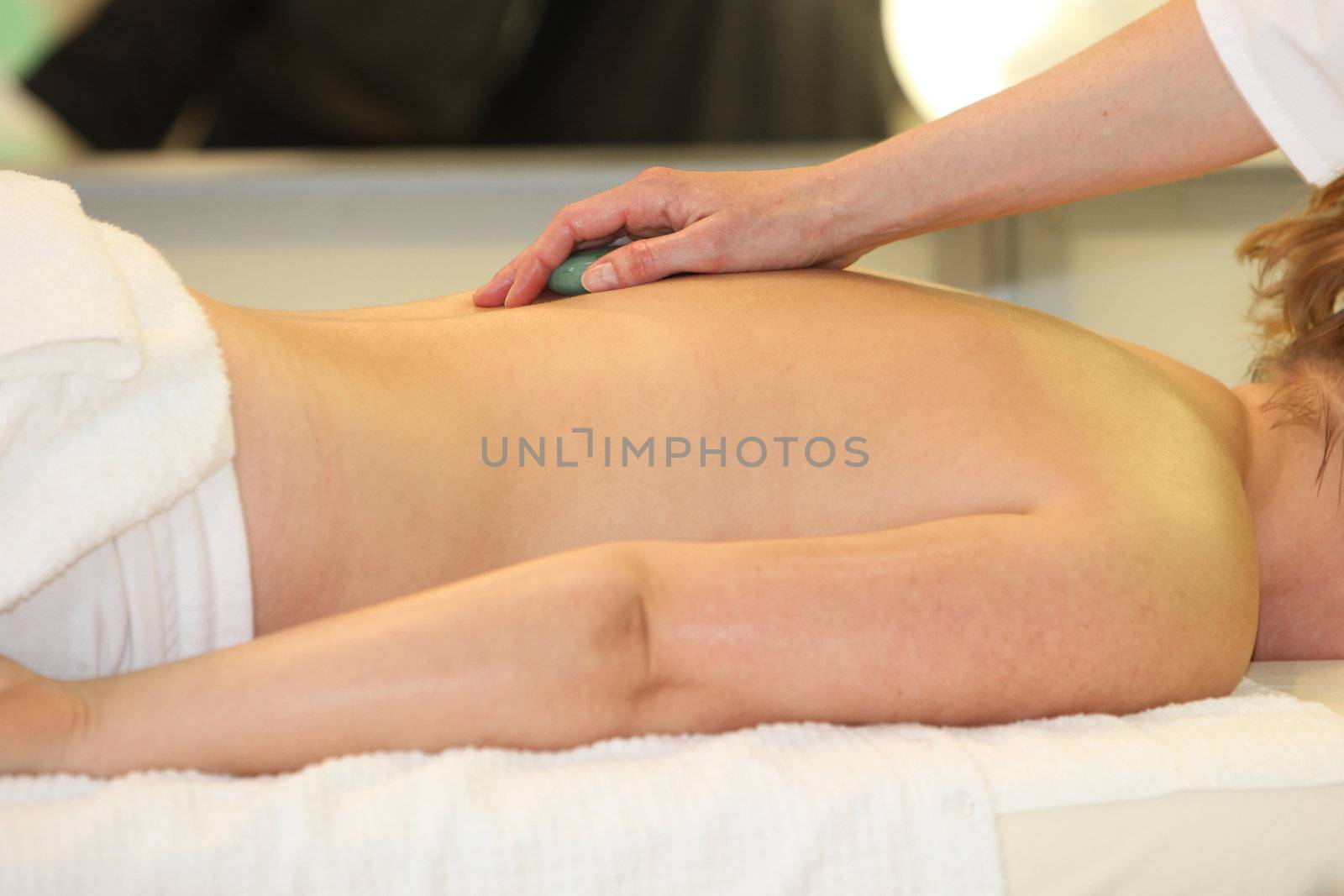 A woman receives a cosmetic treatment and massage with hot stones - close-up