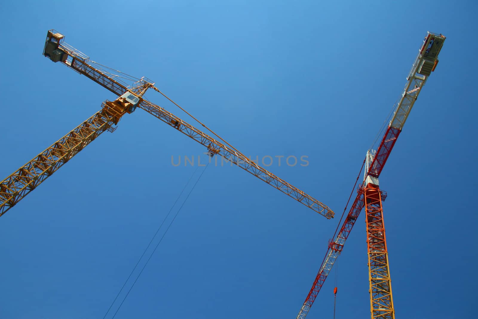 Two building cranes against cloudless sky