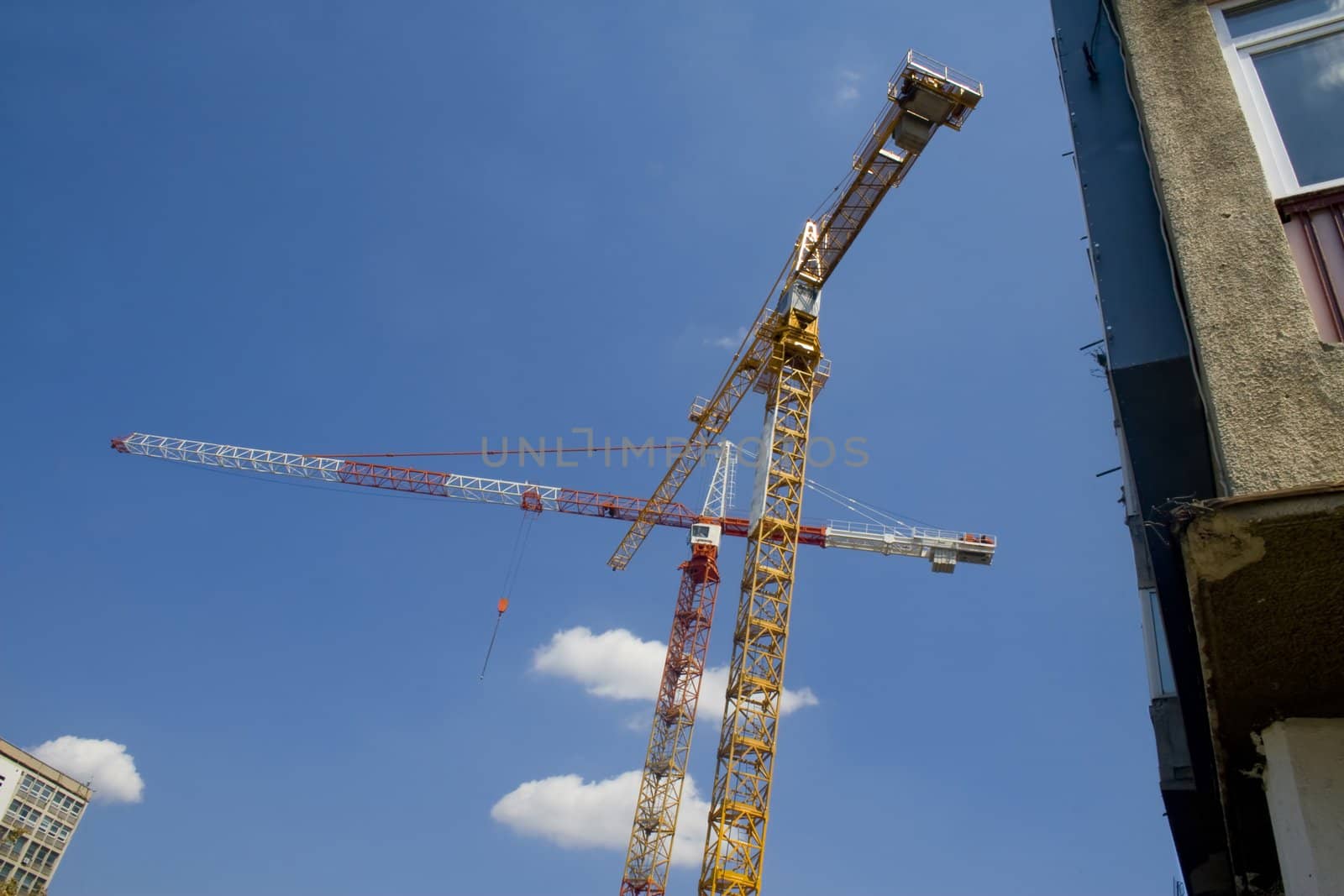 Two cranes with old apartment building to right of frame