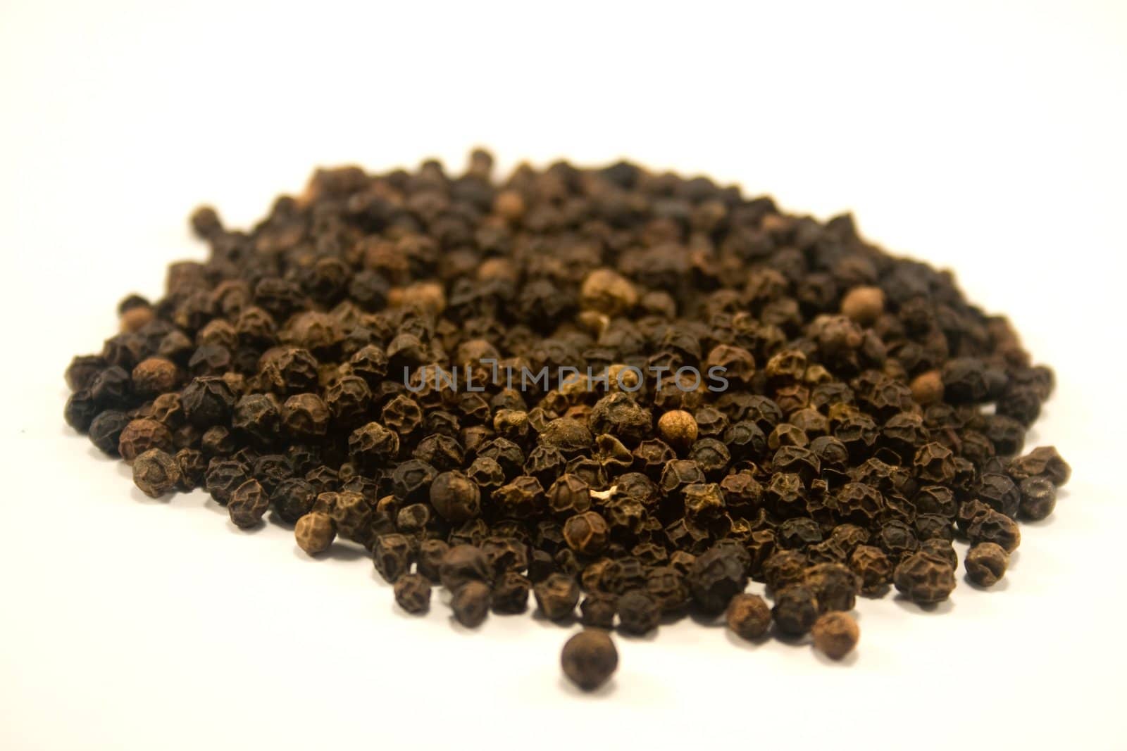 whole black peppercorns isolated against white
