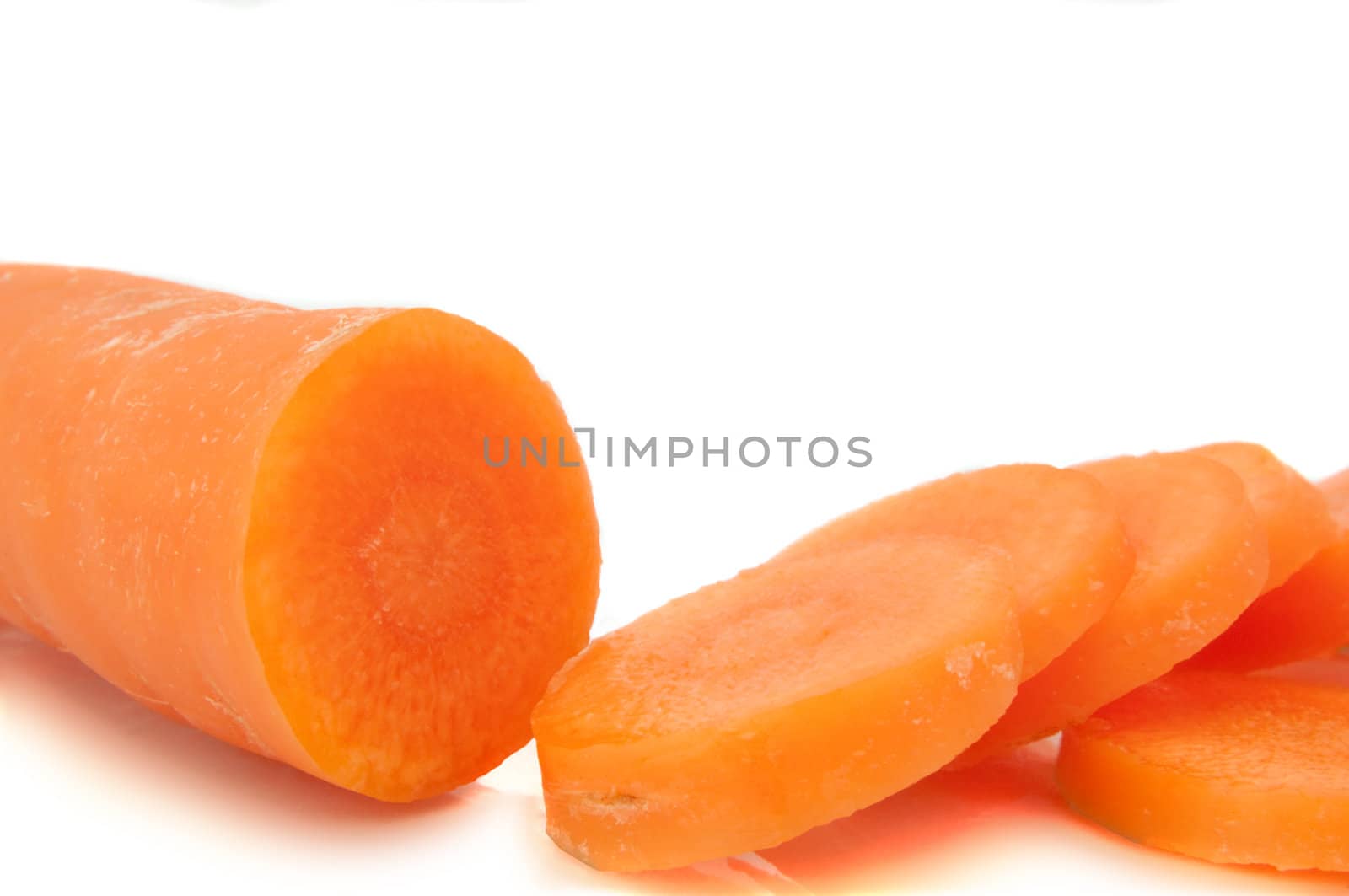 Close and low level of a partially sliced carrot arranged over white.