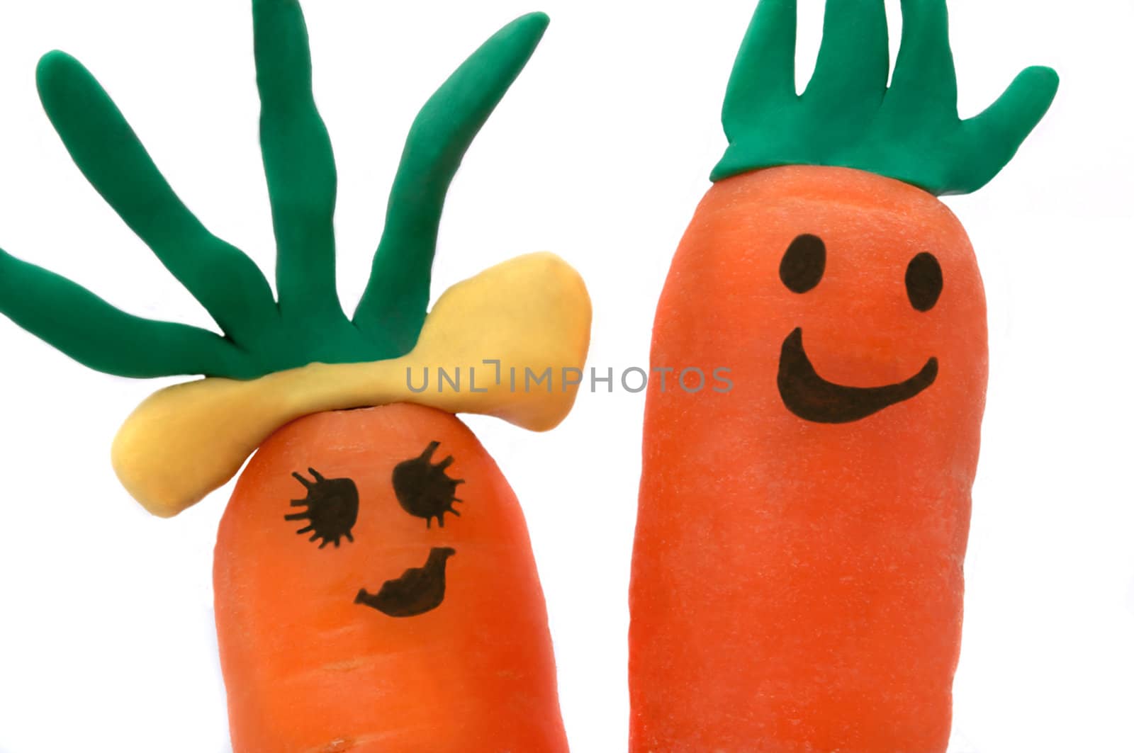 Close up of two carrots with smiling faces against a white background.