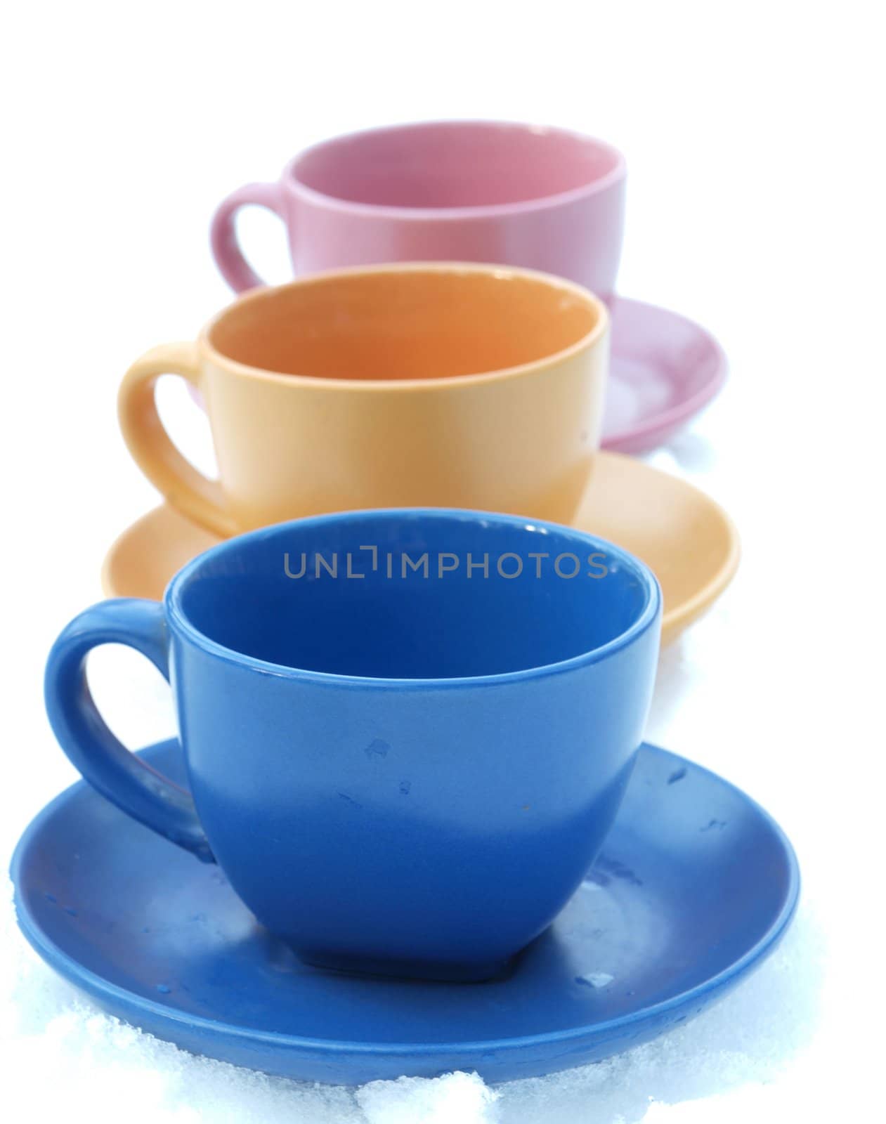 Violet, orange and blue cups on a snow   