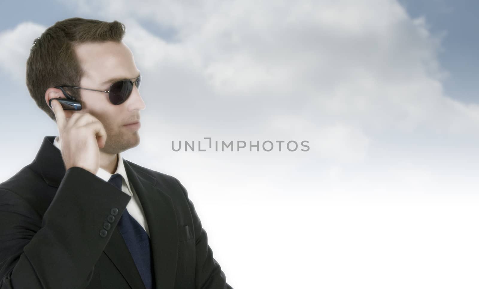 handsome businessman with sunglasses and bluetooth on abstract background