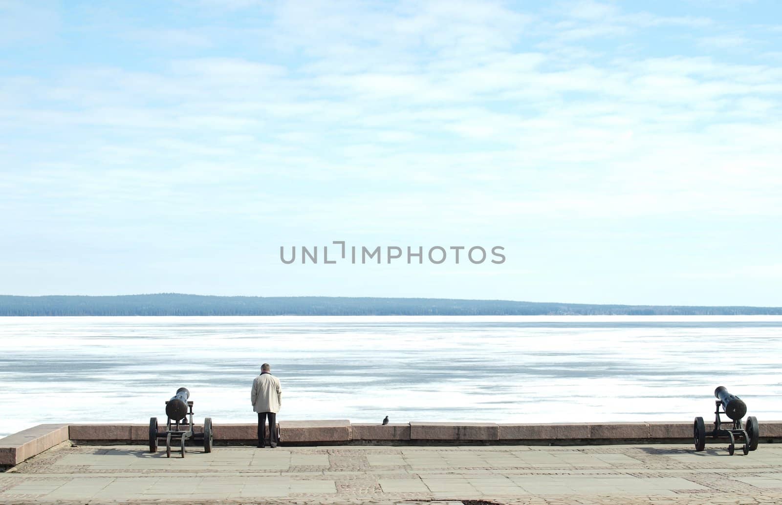 The man, two guns and the pigeon on coast of lake. Quay of Petrozavodsk, Russia            
