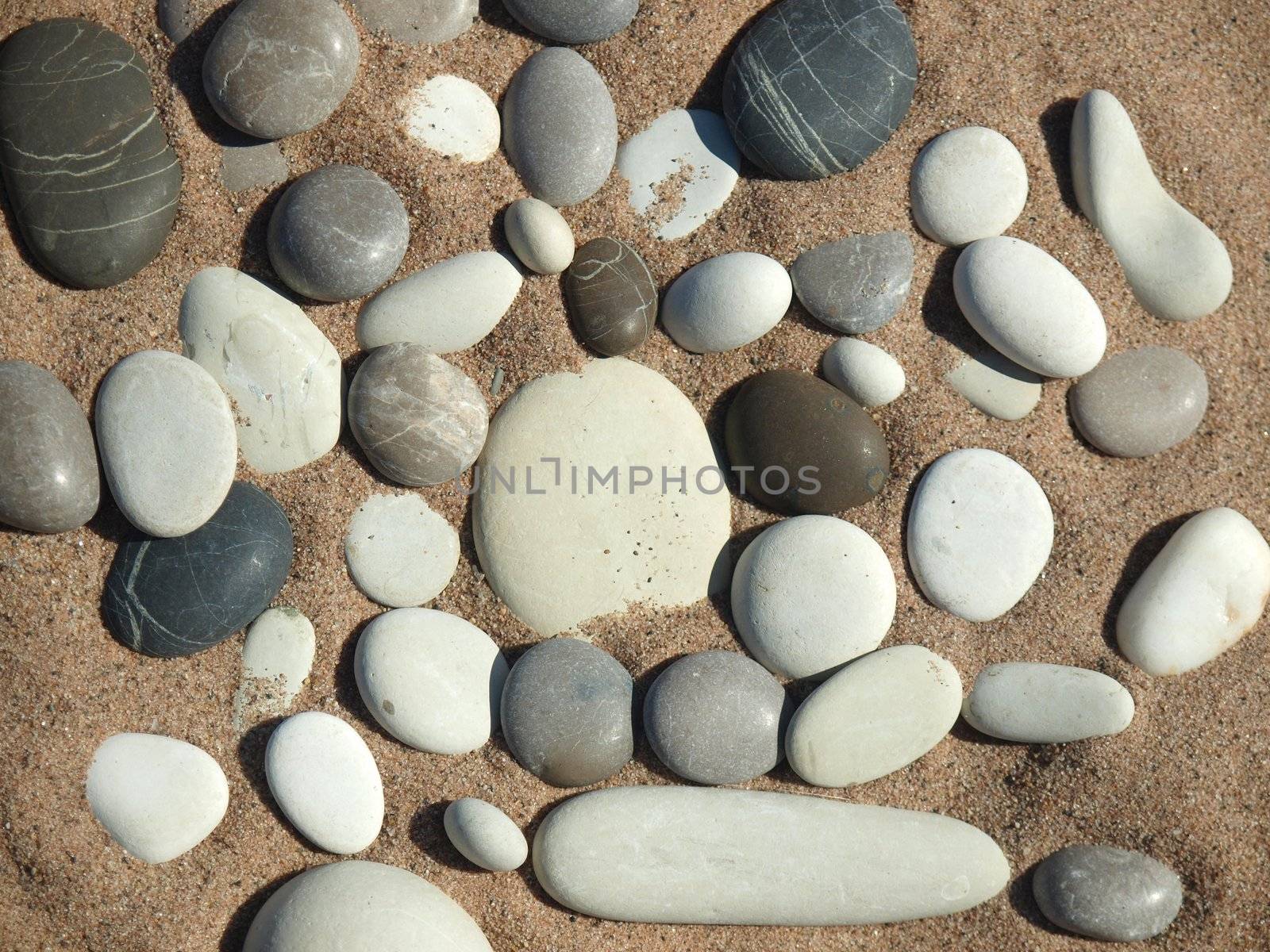 Black, white and grey pebble on sand on coast of lake    