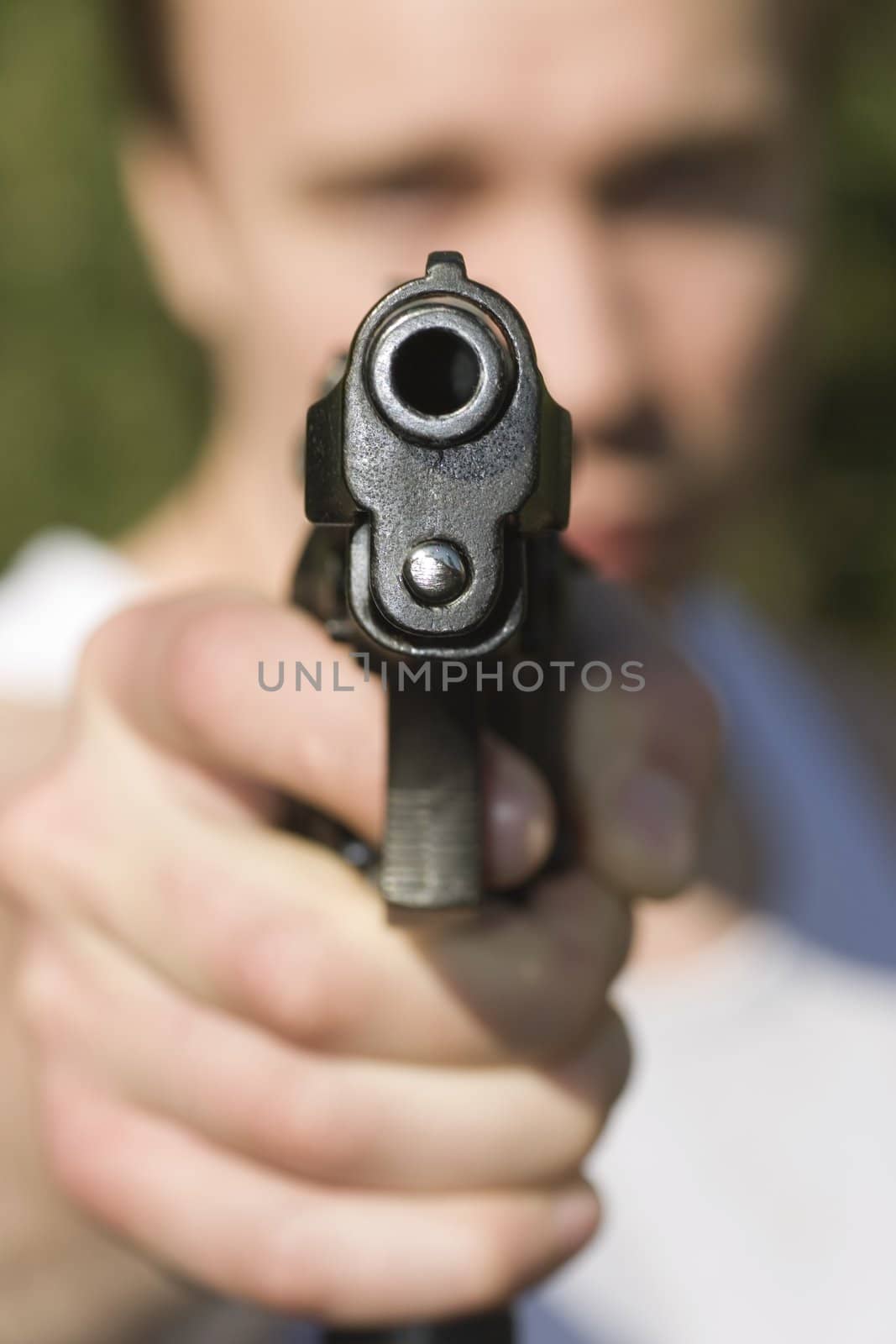 A man holding a pistol and pointing it at the camera.
