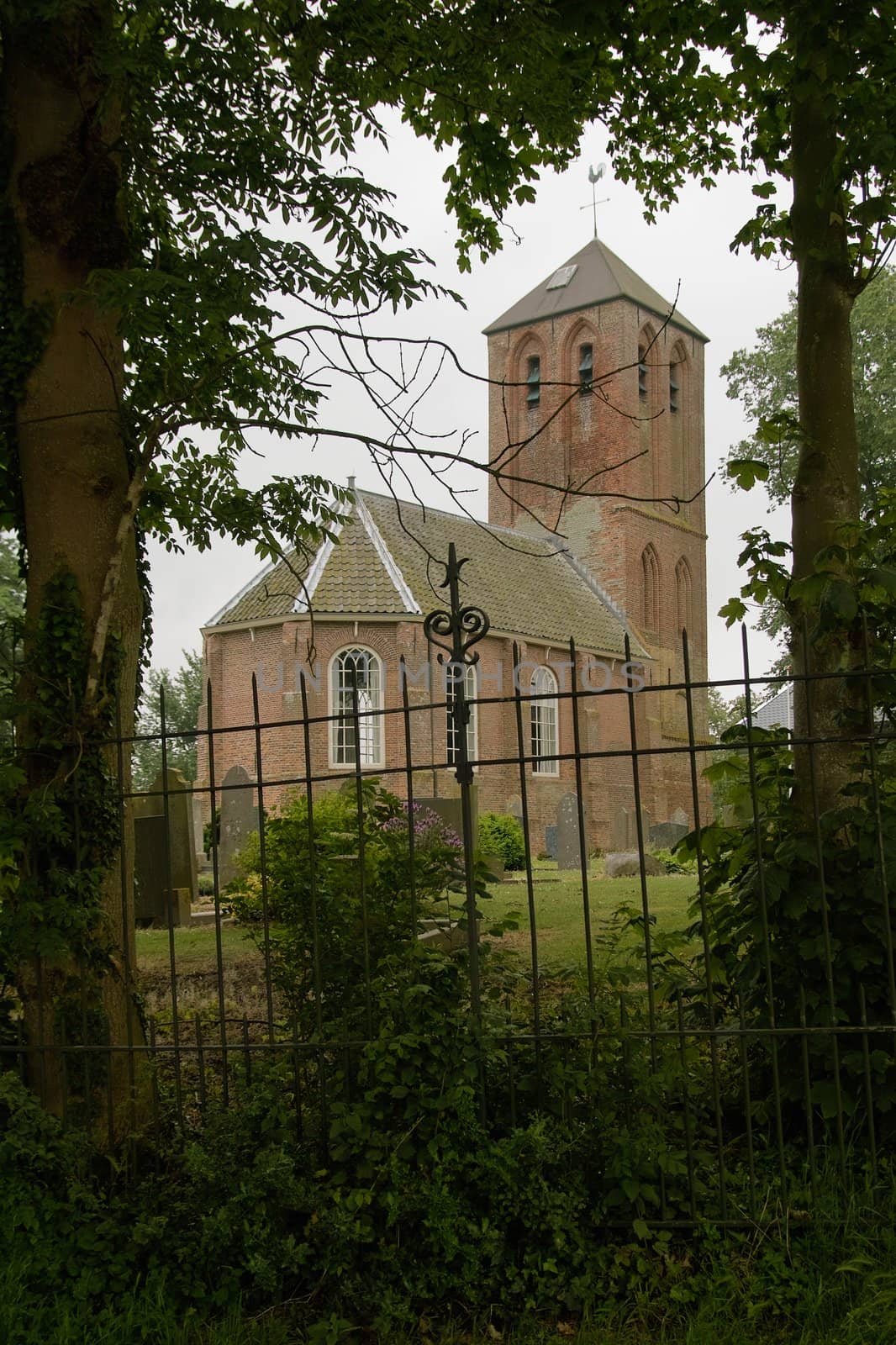 An old medieval church in the village of Westerland, seen through the trees that surround the graveyard around the church