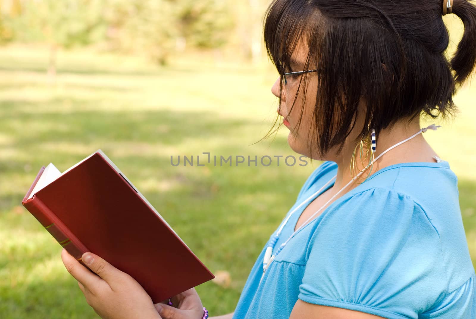 Closeup of a nine year old girl reading a novel outside