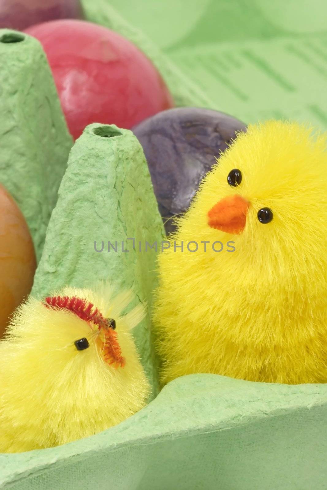 Colorful eggs in a carton with toy chicken
