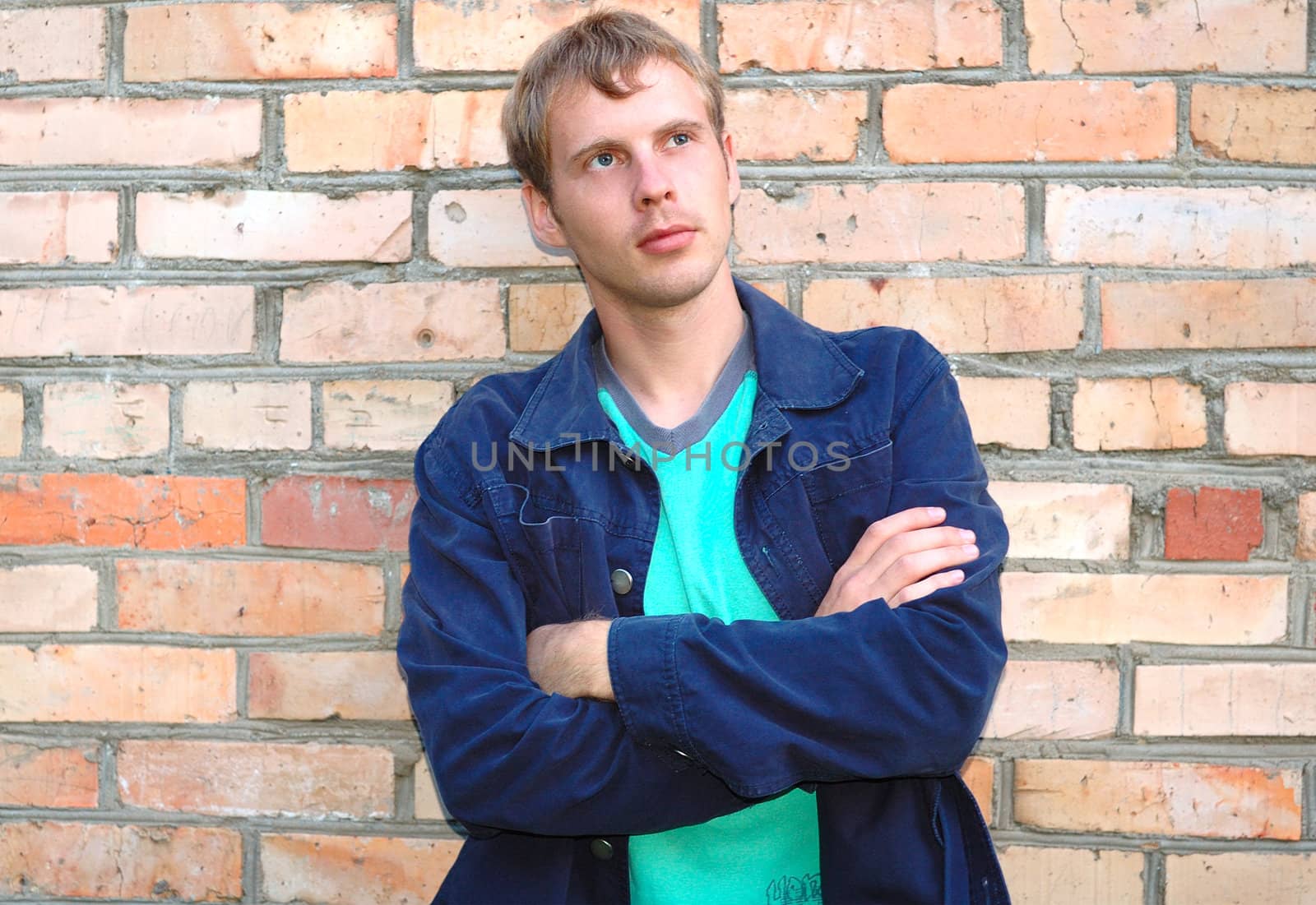 Young stylish man with blonde hair stand near brick wall.