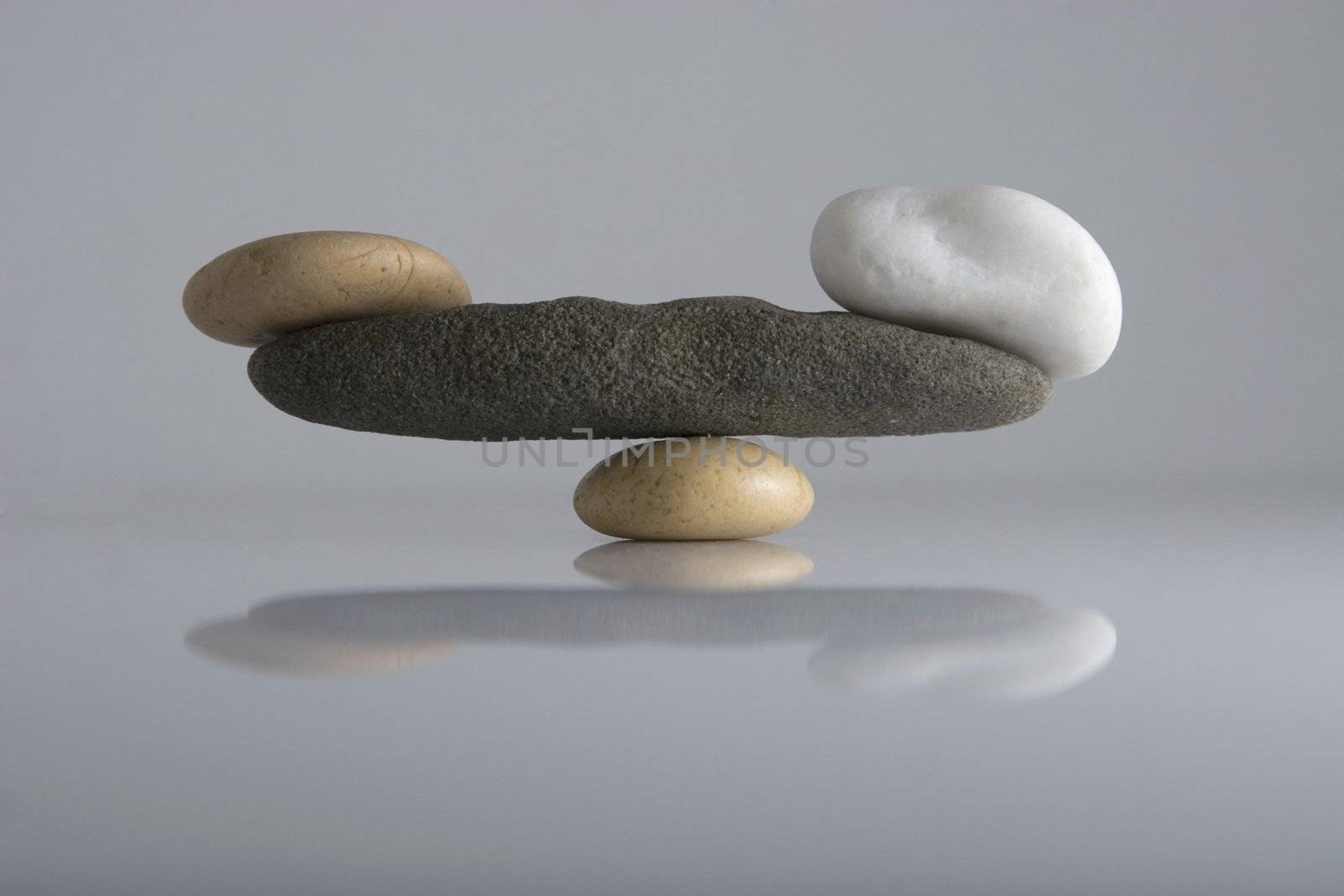 Front view of balancing stones over a white background with reflection