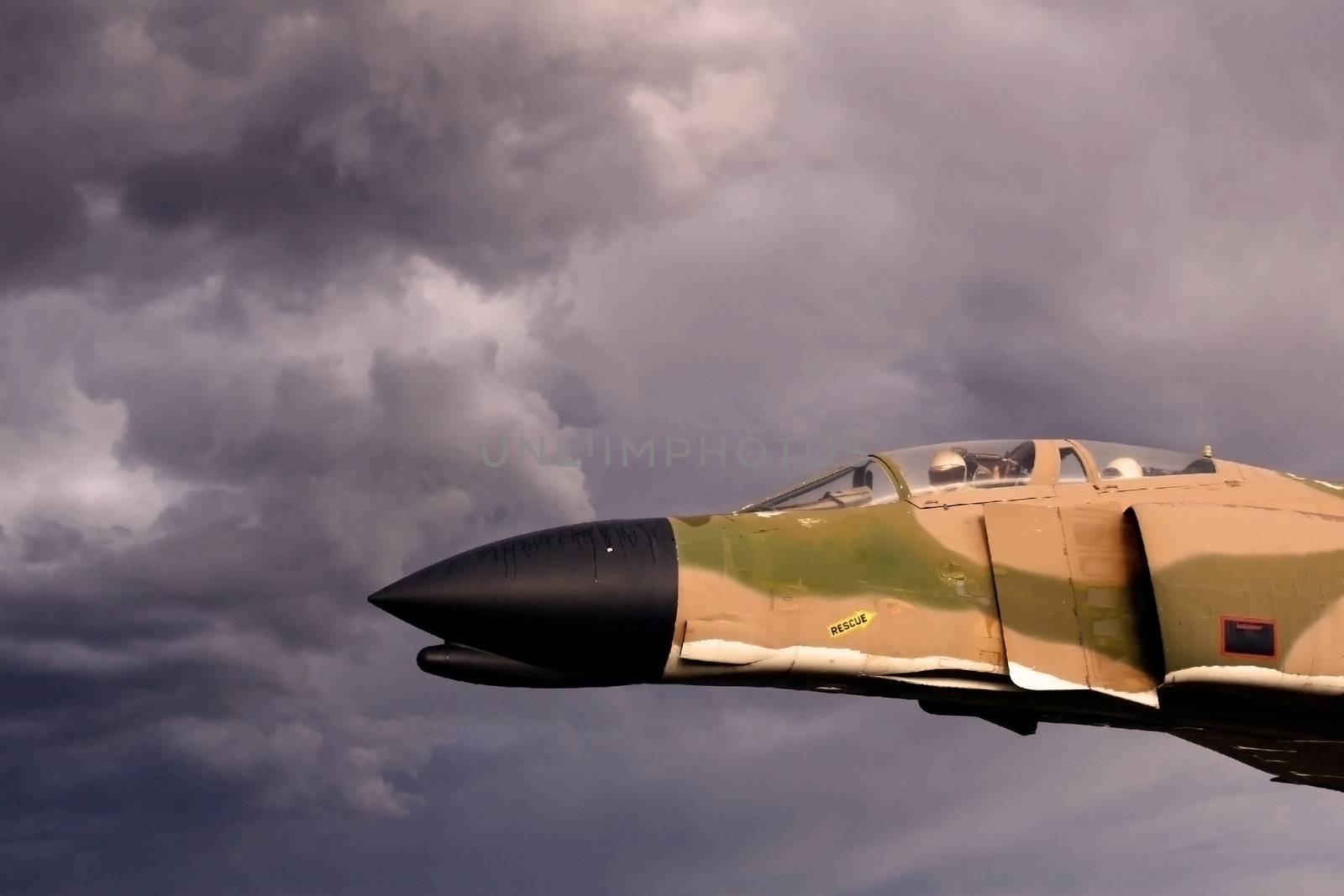 Vintage Vietnam era fighter plane with pilot and navigator seems to be flying into ominous thunderstorm