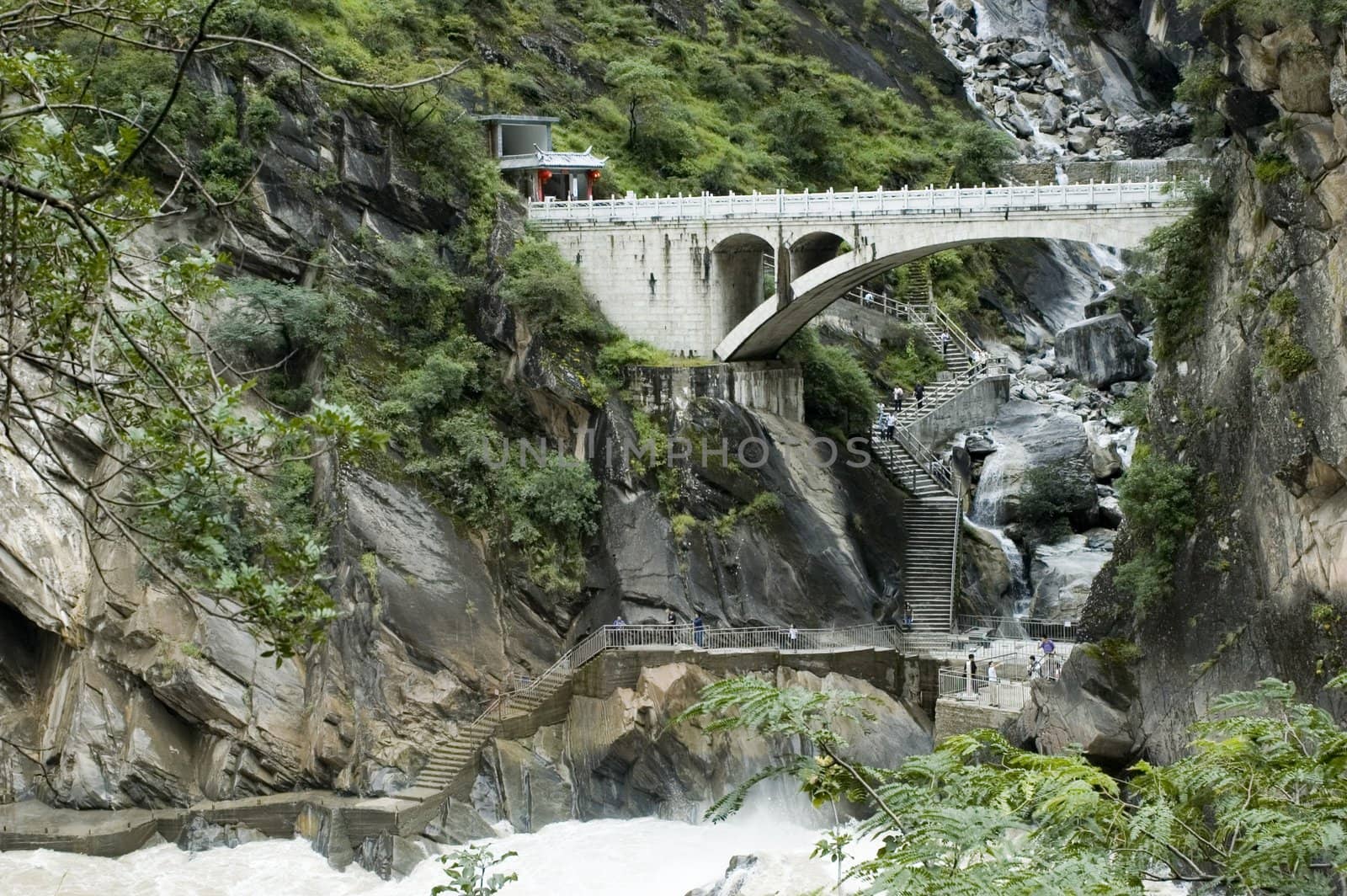 Sino-Tibetan mountains in Yunnan province, near Lijiang city, China. Bridge in ancient Chinese style over river.