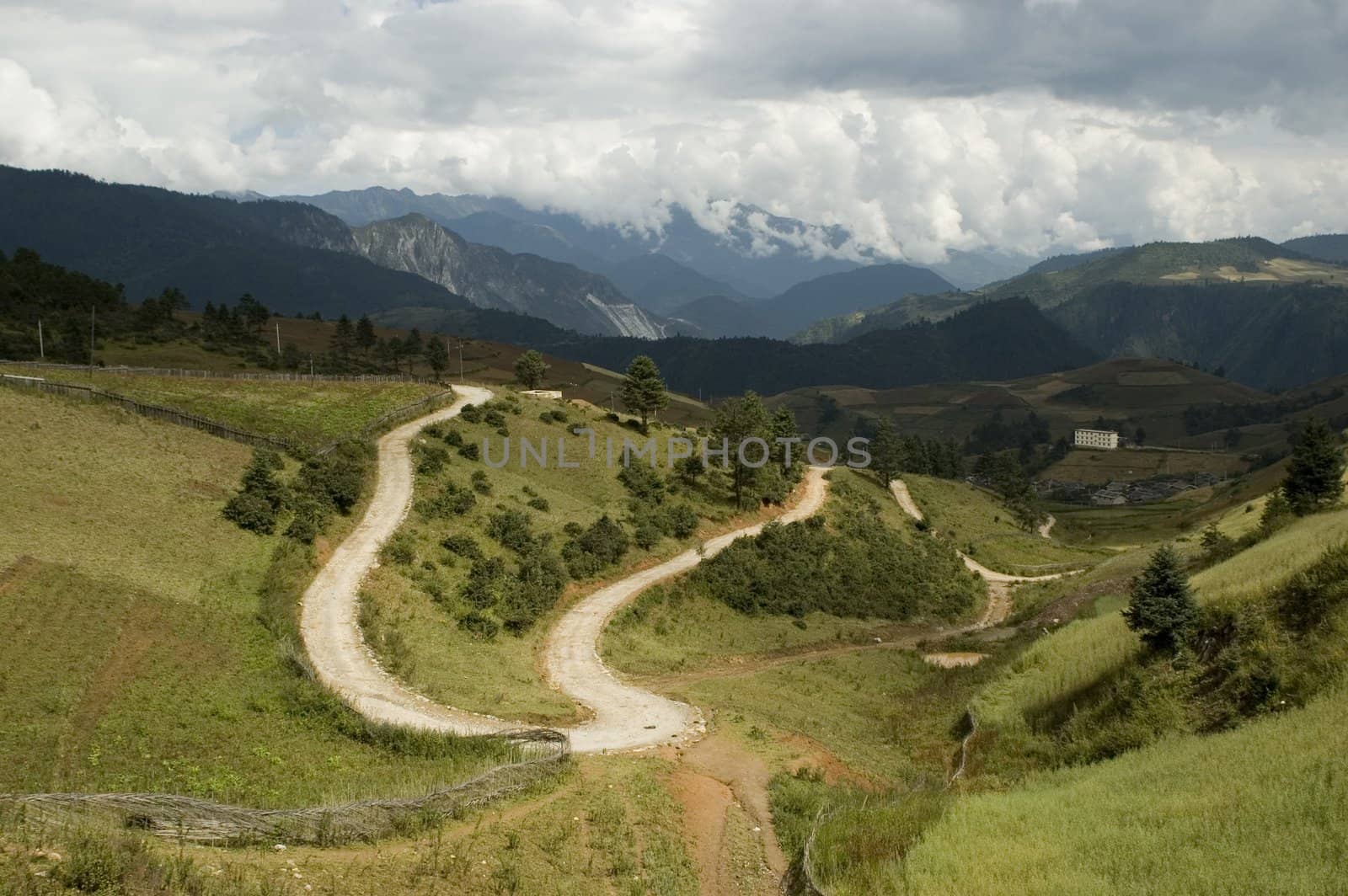 Yunnan province, China - beautiful landscape - roads, trees, meadows and high mountains surrounding village.