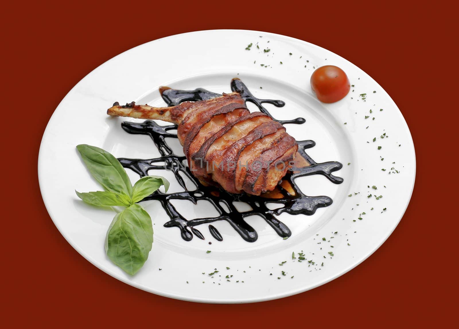 Close up of a rib of pork with basil and cherry tomato.