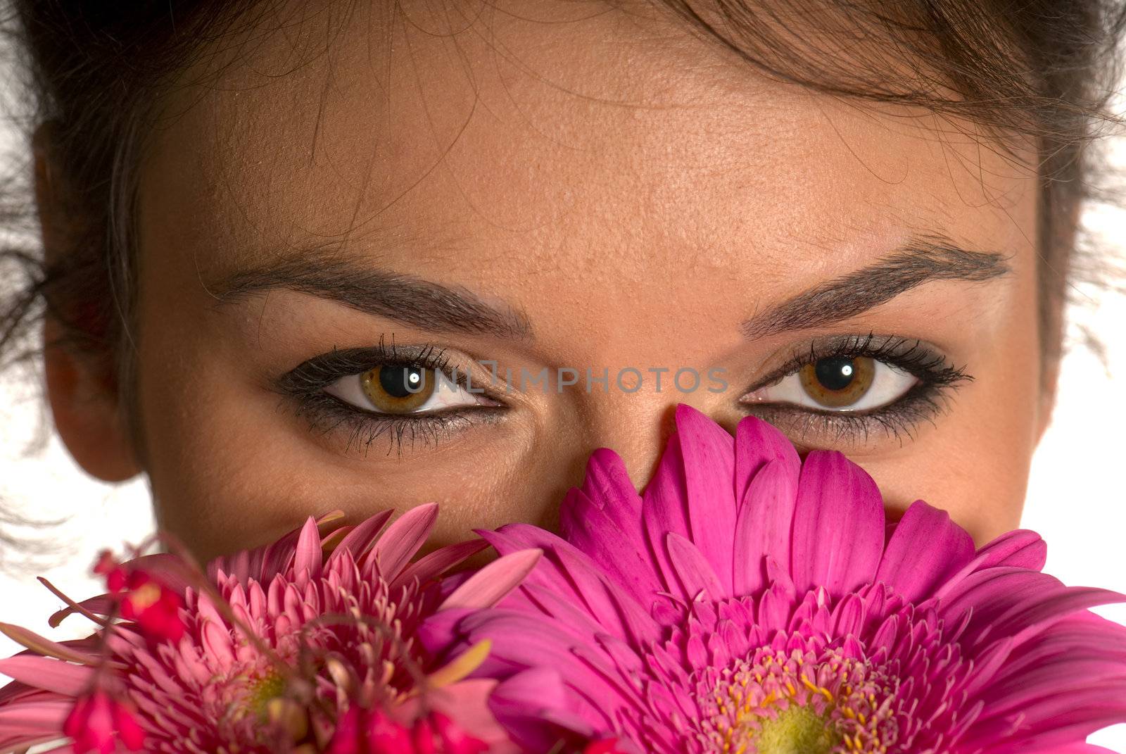 Beautiful young woman smelling flowers over white background