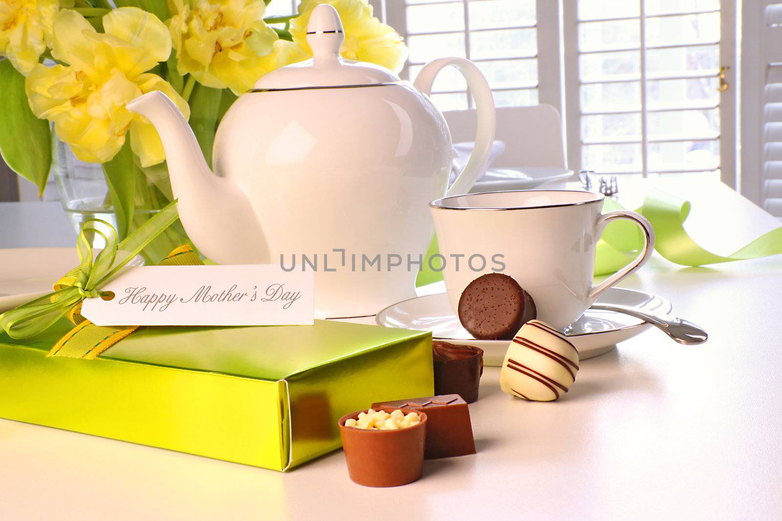 Box of chocolates on table with tea set and tulips