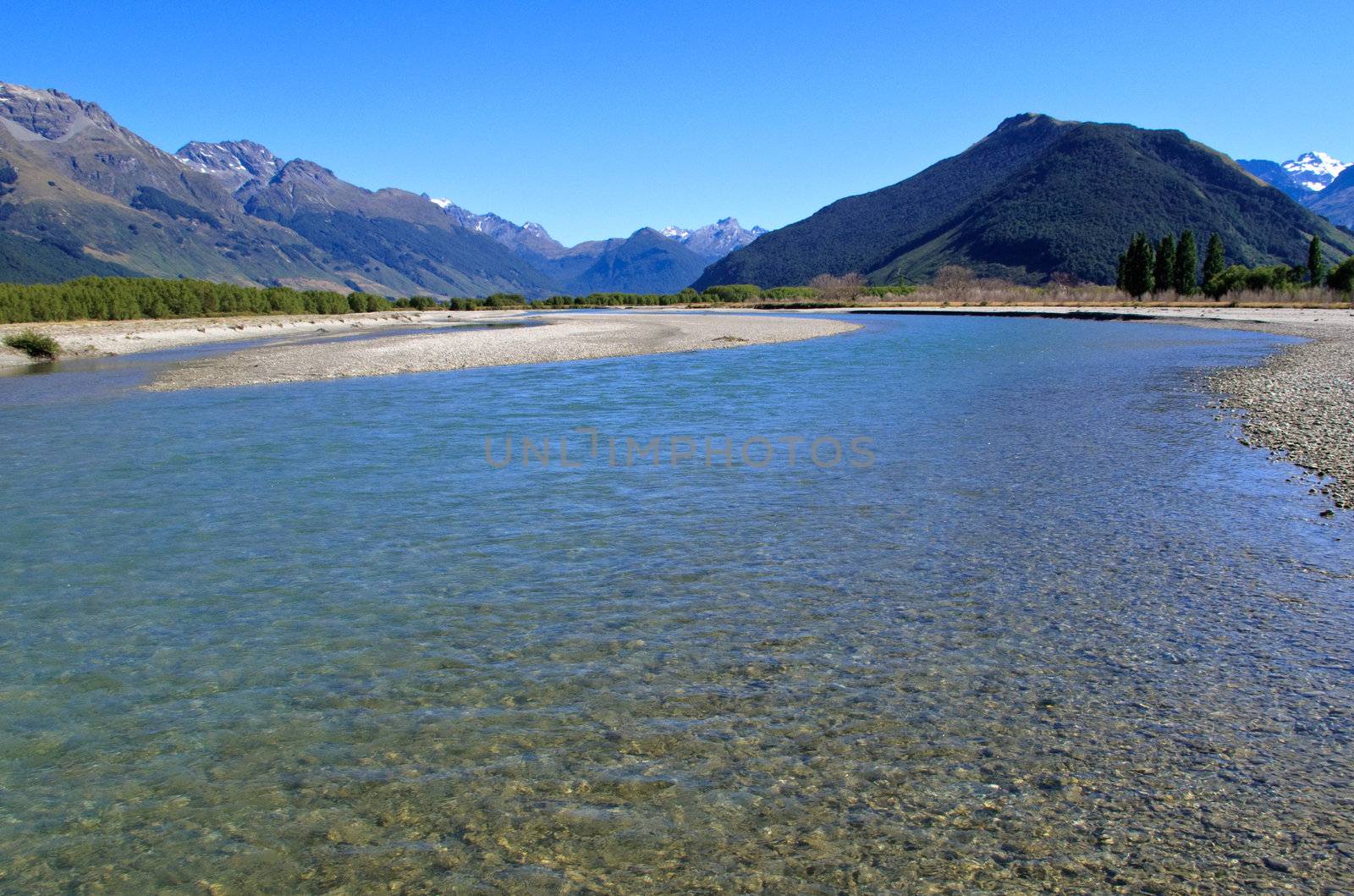 Mountain range tower over tranquil river near in Paradise area of New Zealand