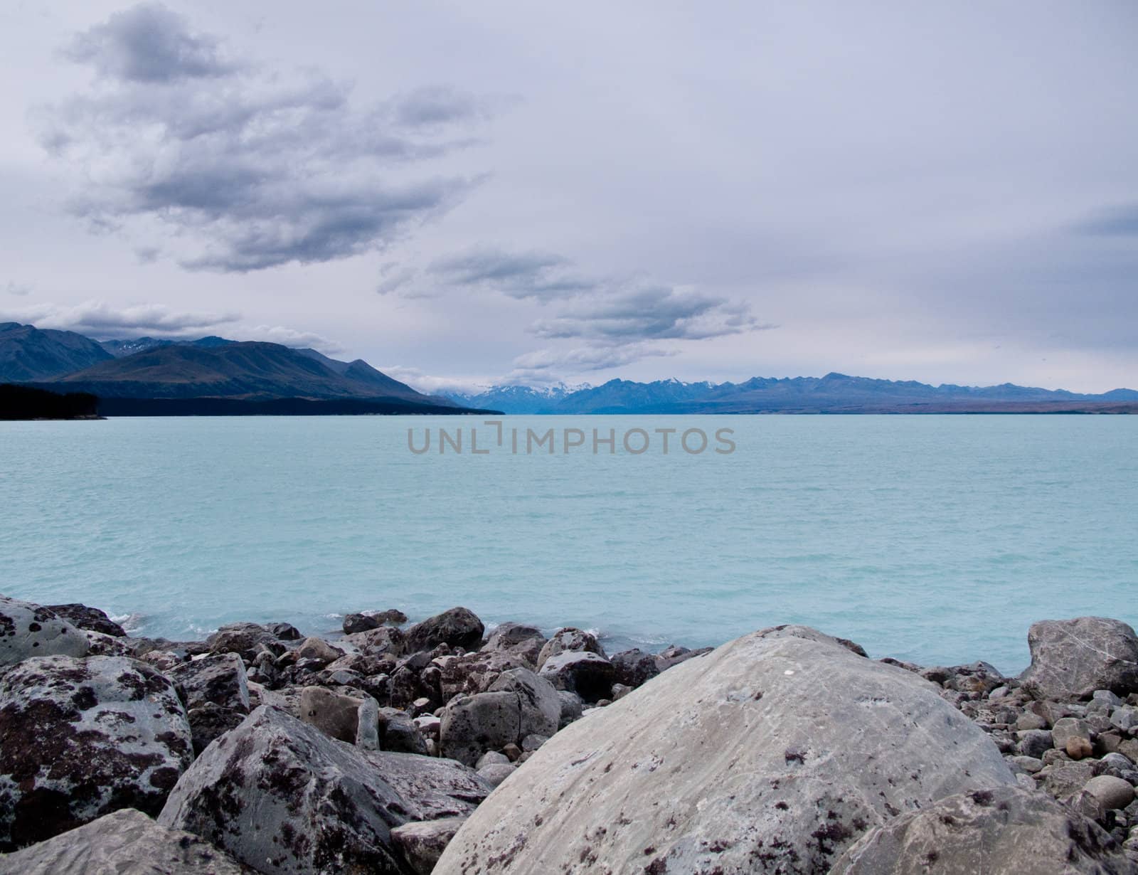 Mount Cook in New Zealand surrounded by clouds with a blue lake