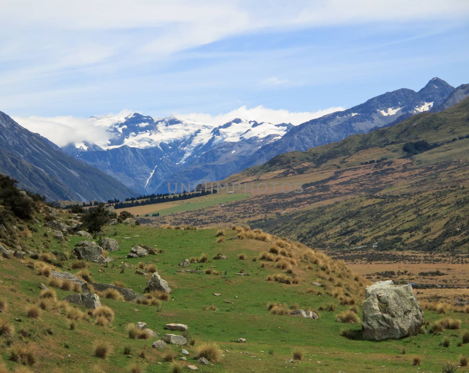 Mount Cook in New Zealand surrounded by clouds over a grassy plain