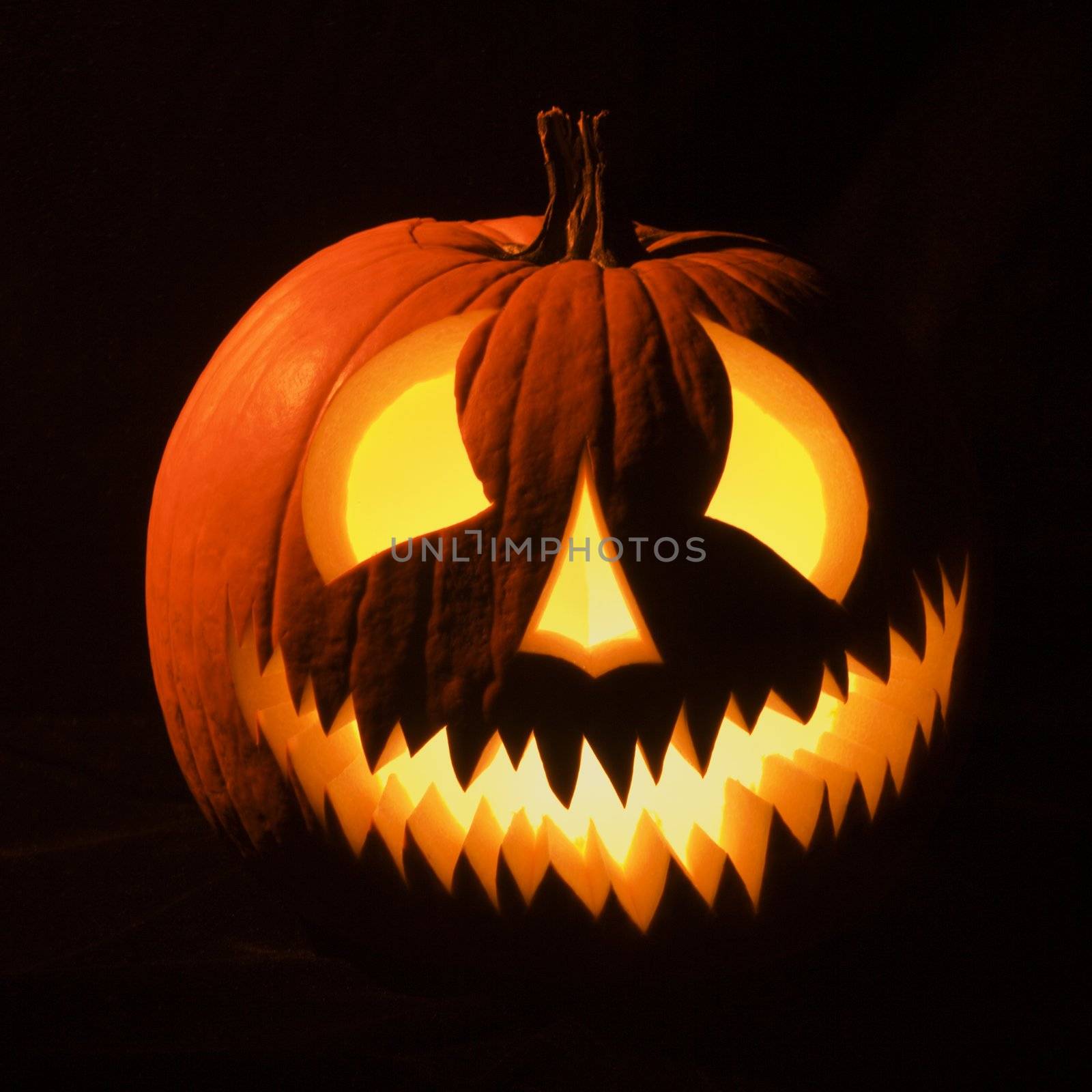 Carved Halloween pumpkin glowing in the dark.