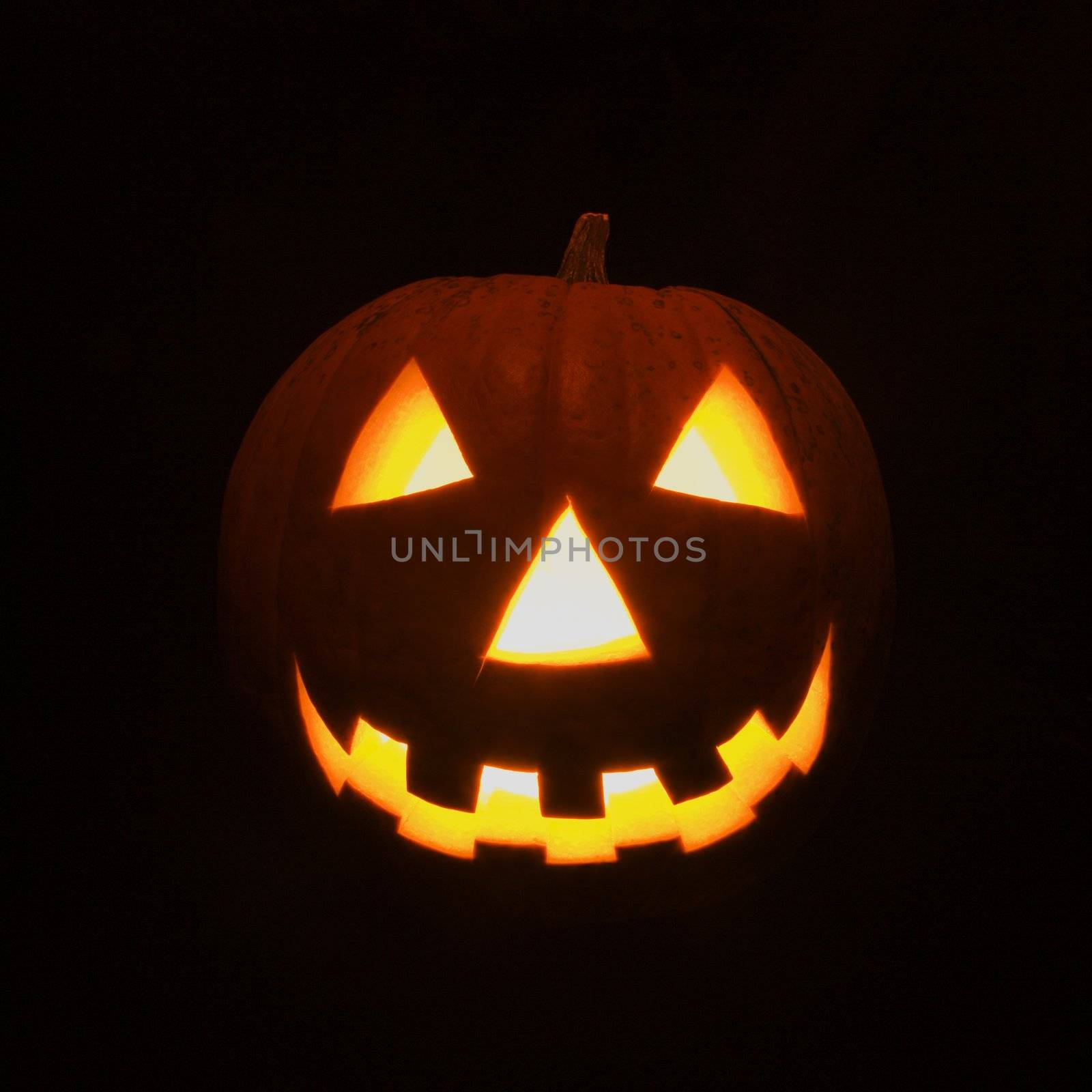 Carved Halloween pumpkin glowing in the dark.